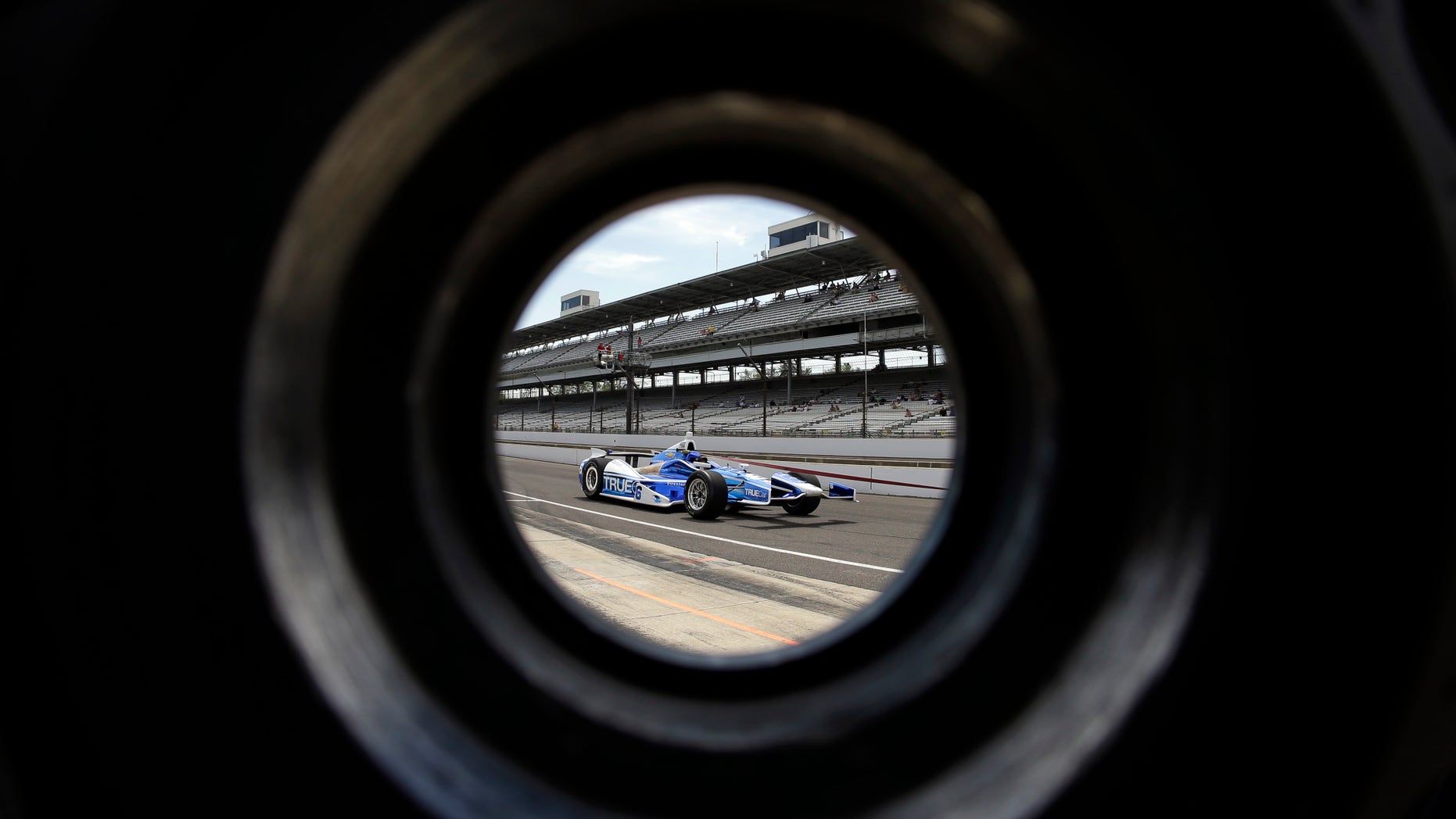 The car driven by Sebastian Saavedra, of Colombia, is seen through a wheel as its pulled through the pit area during practice for the Indianapolis 500 auto race at the Indianapolis Motor Speedway in Indianapolis, Wednesday, May 15, 2013. (AP Photo/Darron Cummings)
