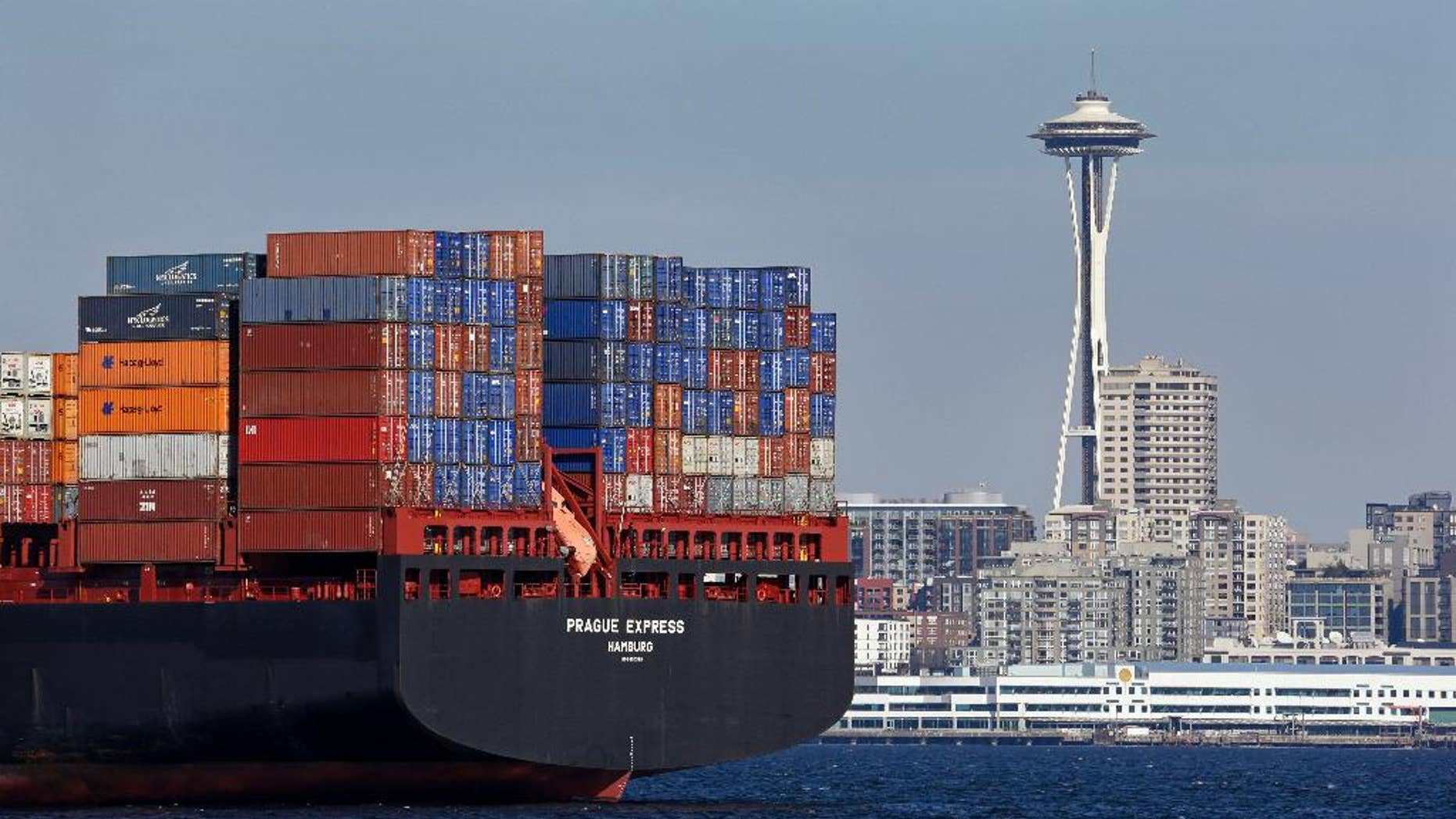 FILE - In this Feb. 15, 2015 file photo, the Space Needle towers in the background beyond a container ship anchored in Elliott Bay near downtown Seattle. The Commerce Department releases international trade data for January on Friday, March 6, 2015. (AP Photo/Elaine Thompson, File)