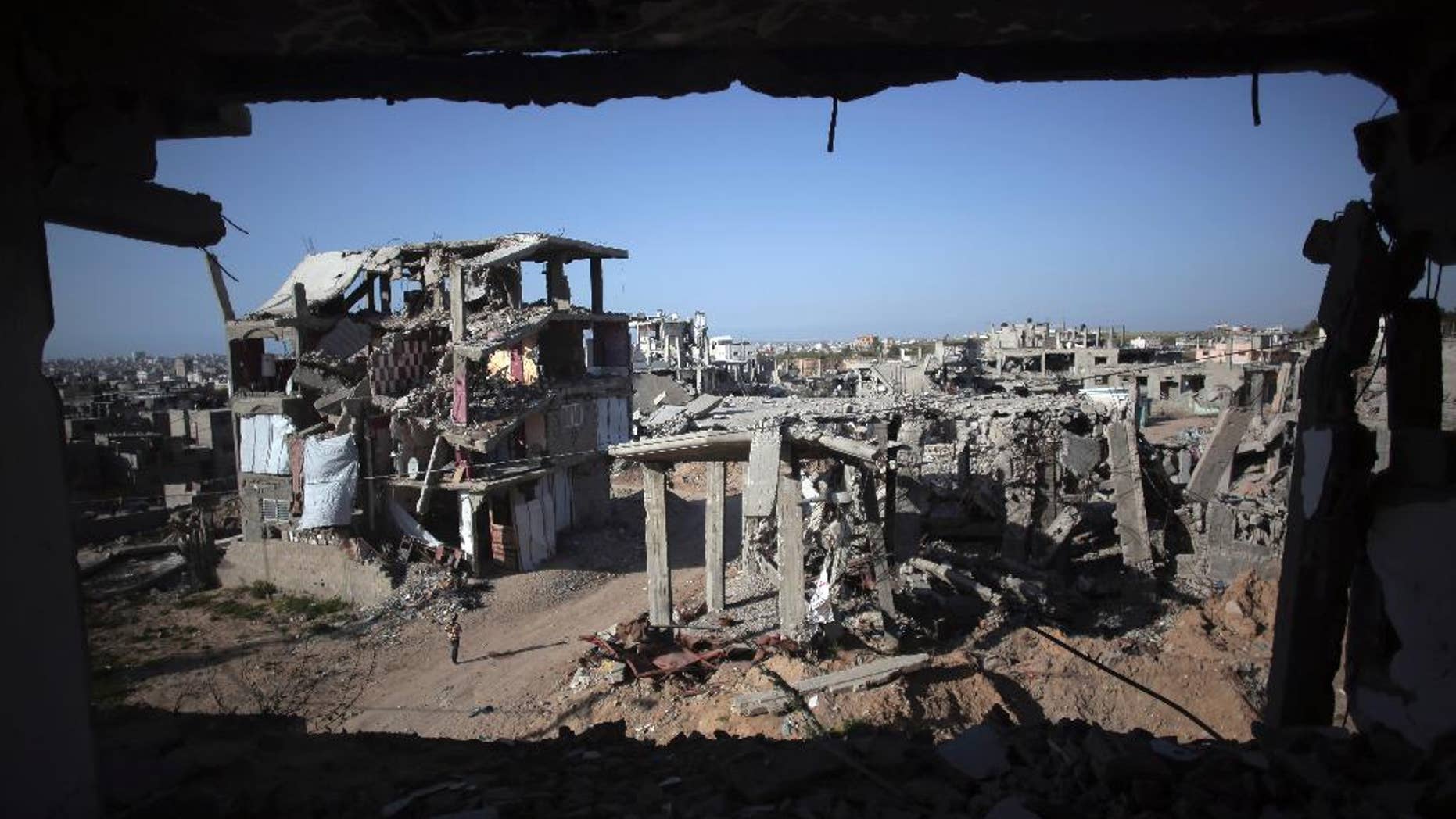 File - In this March 30, 2015 file photo, a Palestinian girl walks next to destroyed houses, in the Shijaiyah neighborhood of Gaza City. The International Monetary Fund said in a Tuesday, May, 19, 2015 report, that reconstruction of the Gaza Strip is going “far more slowly than expected” after a devastating war between Israel and the Hamas militant group last year. The IMF said that just over a quarter of $3.5 billion pledged for reconstruction has been disbursed and urged donors to fulfill their pledges. (AP Photo/Khalil Hamra, File)