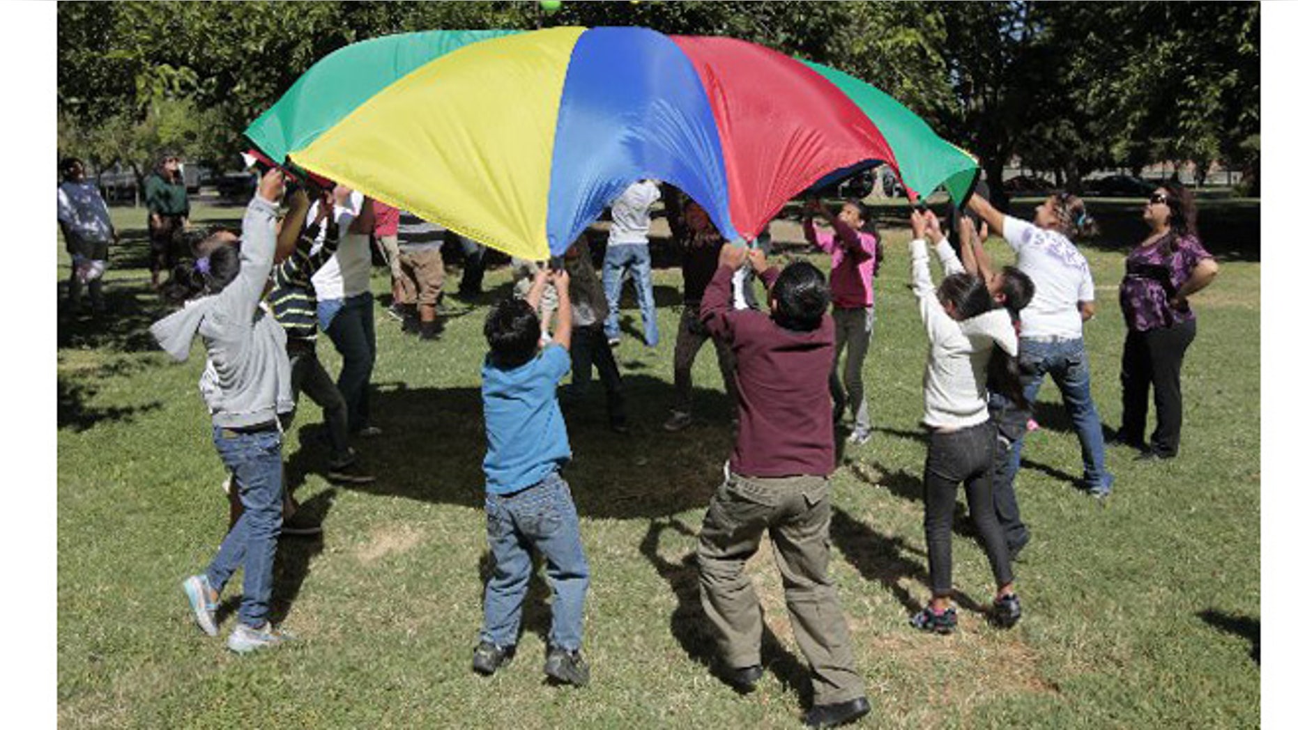 Children and adults uses a play parachute as past of an exercise activity during a wellness program run jointly by the La Familia Counseling Center and the YMCA in Sacramento. The program is funded by 2004's Proposition 63. A fifth of the revenue from the measure goes to activities, like wellness programs. (AP Photo/Rich Pedroncelli)
