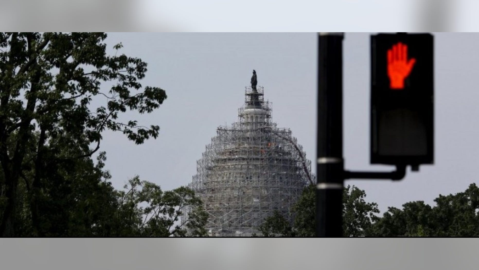 A pedestrian red light is seen near the U.S. Capitol dome, currently under renovation, in Washington June 8, 2015. (REUTERS/Carlos Barria)