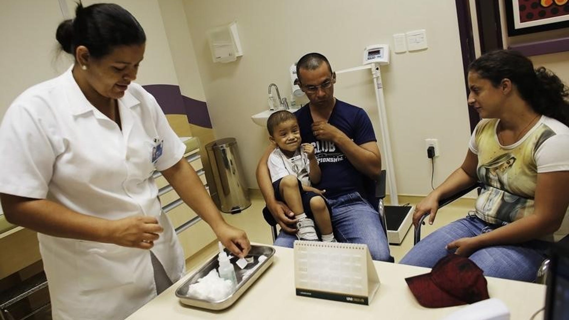 Rafael Freitas, a three-year-old cancer patient, is accompanied by his parents Randerson Freitas and Patriana da Silva (R) while a doctor (L) prepares an injection at the Hospital de Cancer in Barretos, Sao Paulo state March 3, 2015. (REUTERS/NACHO DOCE)