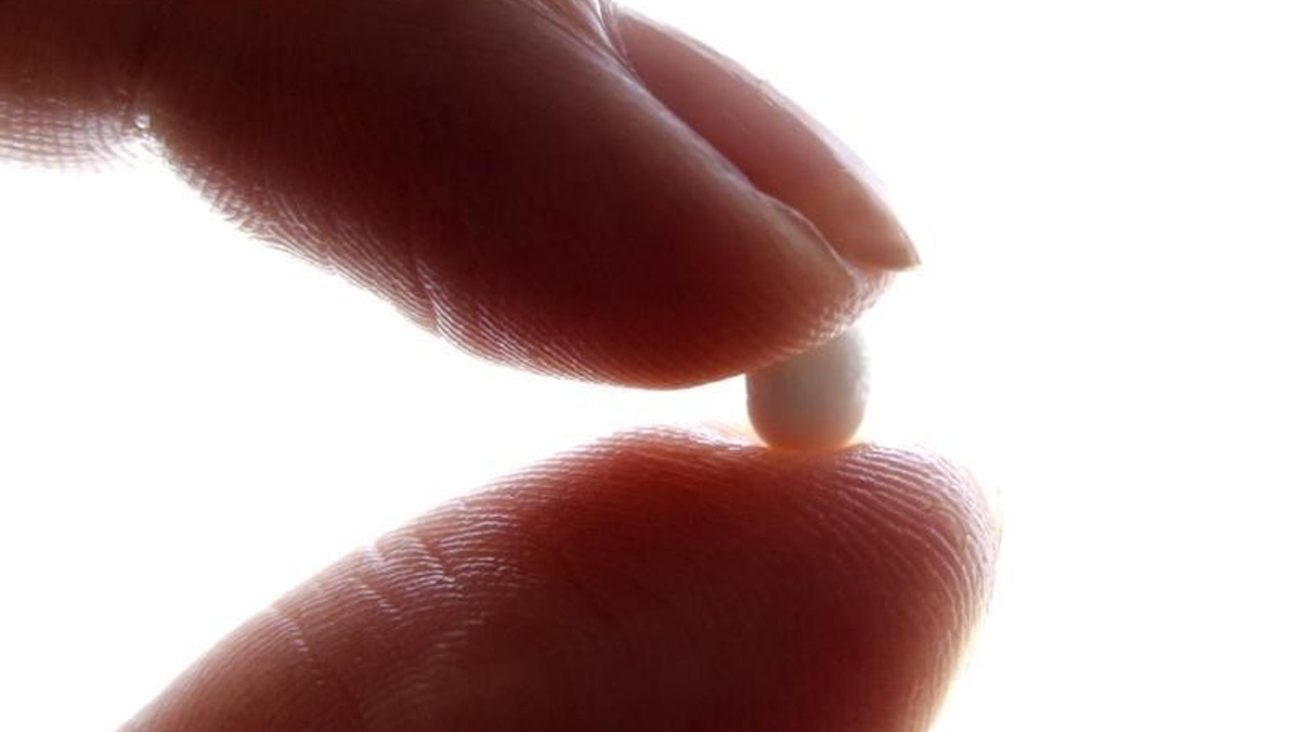 An illustration picture shows a woman holding a birth control pill at her home in Nice January 3, 2013. REUTERS/Eric Gaillard