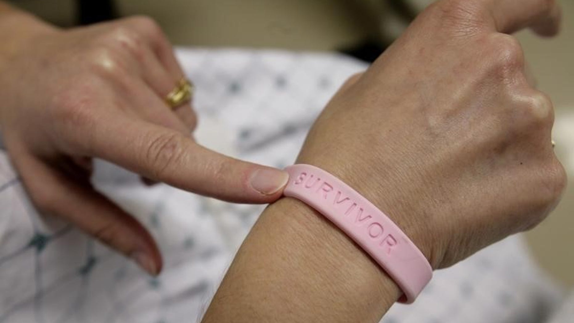 After three operations and four rounds of chemotherapy at Georgetown University Hospital, cancer patient Deborah Charles shows off her breast cancer survivor bracelet during a hospital appointment in Washington May 23, 2007. REUTERS/Jim Bourg