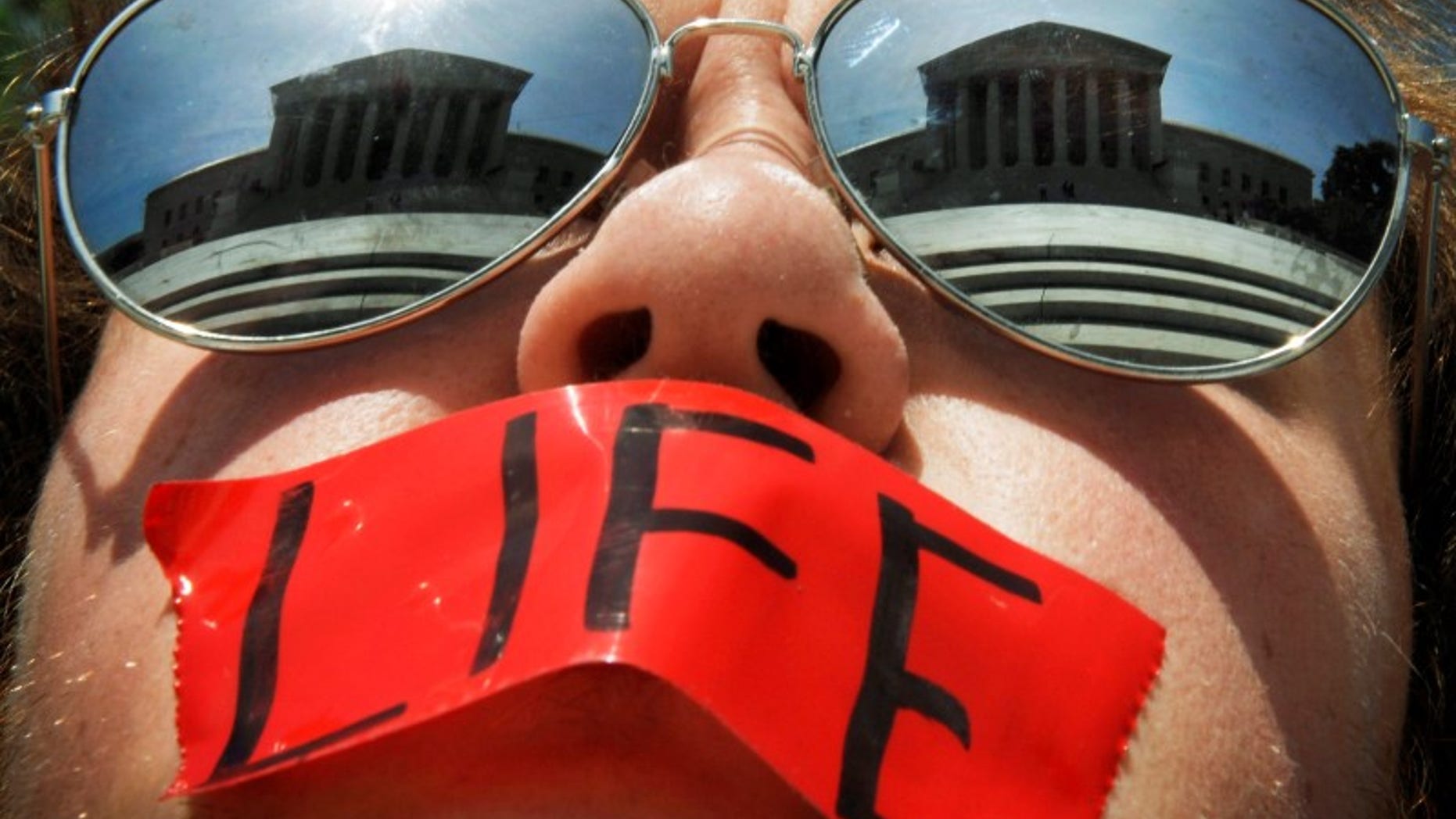 Anti-abortion activist Craig Kuhns wears mirrored sunglasses and a piece of tape over his mouth as he stands in front of the US Supreme Court building in Washington, in this June 1, 2009 file photo.REUTERS/Jonathan Ernst/Files