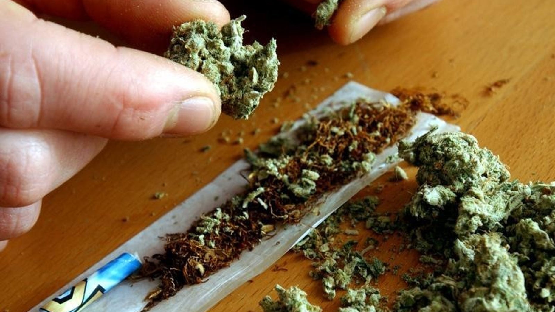 A man makes a cannabis cigarette in the image above.