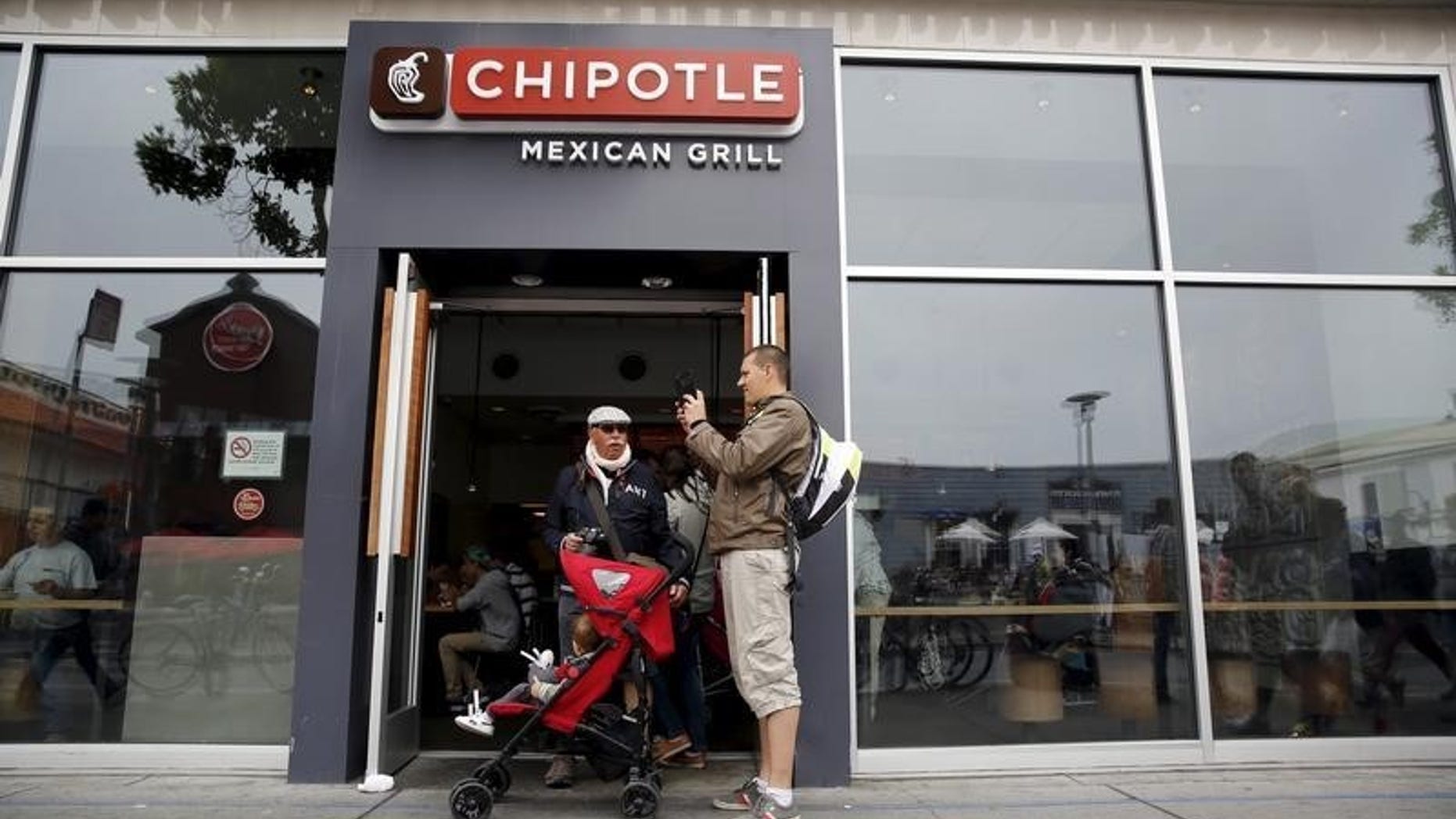 A man snaps a photograph at the entrance to Chipotle Mexican Grill in San Francisco, California July 21, 2015. REUTERS/Robert Galbraith