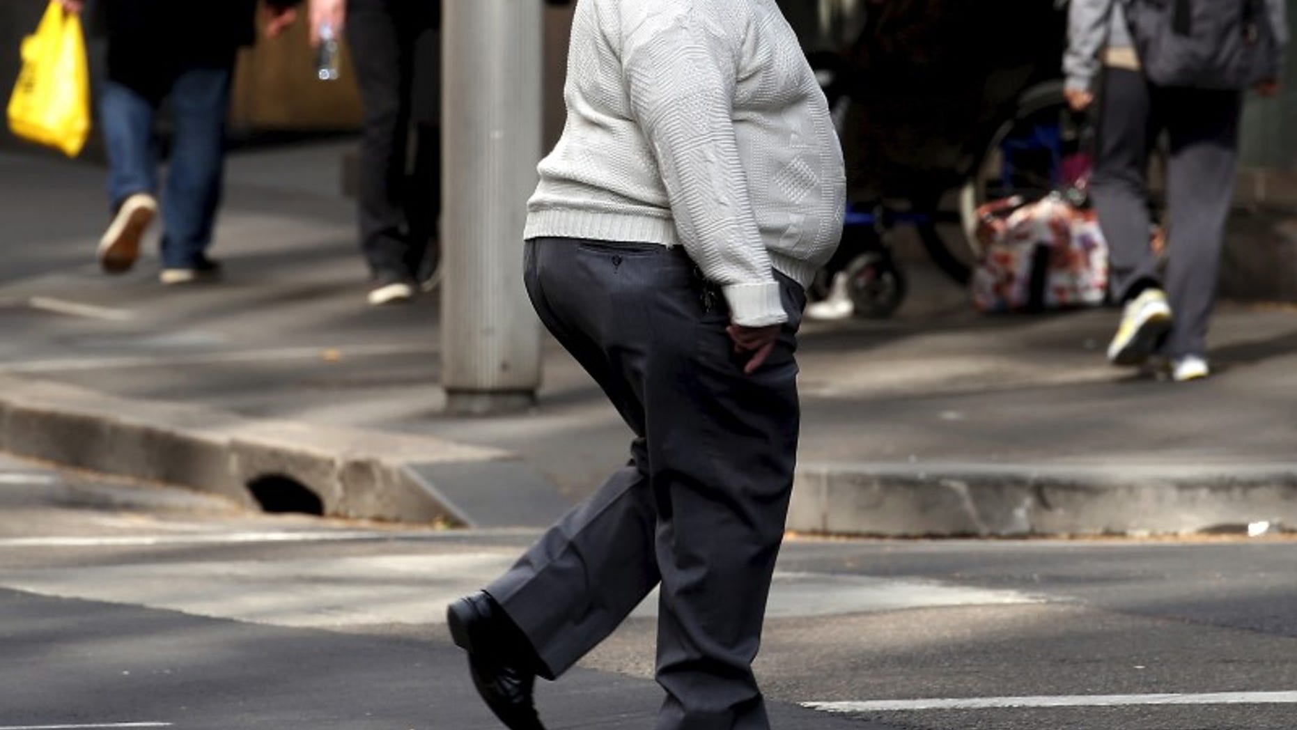 A man crosses a main road as pedestrians carrying food walk along the footpath in central Sydney, Australia, August 12, 2015. REUTERS/David Gray