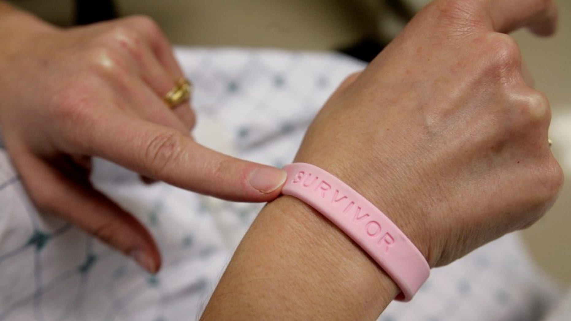 A cancer patient shows off her breast cancer survivor bracelet REUTERS/Jim Bourg