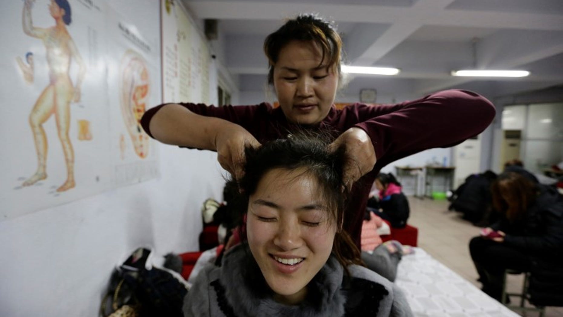 A student presses the acupuncture points on the head of a fellow student as they practise massage on each other during a training course at Huaxia Liangtse Massage Training Center in Zhengzhou, Henan province, February 17, 2014. REUTERS/Jason Lee