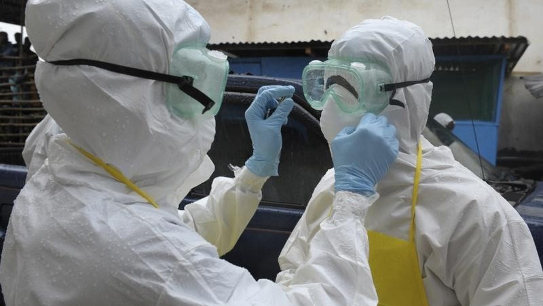 Health workers wearing protective clothing prepare themselves before to carrying an abandoned dead body presenting with Ebola symptoms at Duwala market in Monrovia August 17, 2014. REUTERS/2Tango