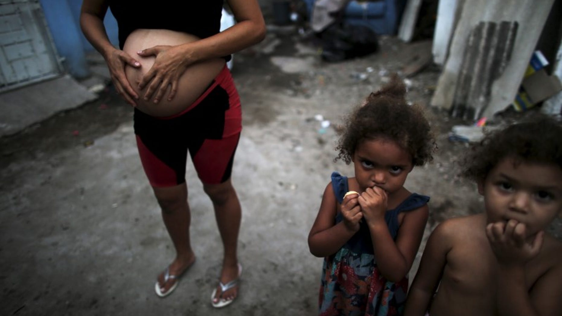 Patricia Araujo, who is seven-months pregnant, stands next to children as they pose in front of their stilt house, a lake dwelling also known as palafitte or 'Palafito', in Recife