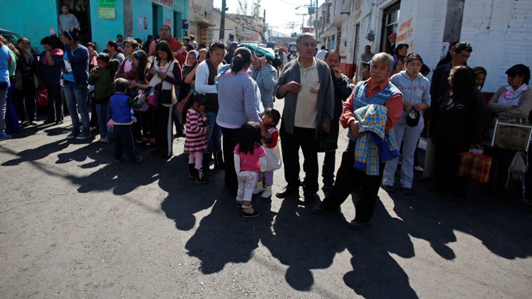 Residents wait in line to receive bedspreads handed out by local authorities at the main plaza of San Lorenzo Acopilco