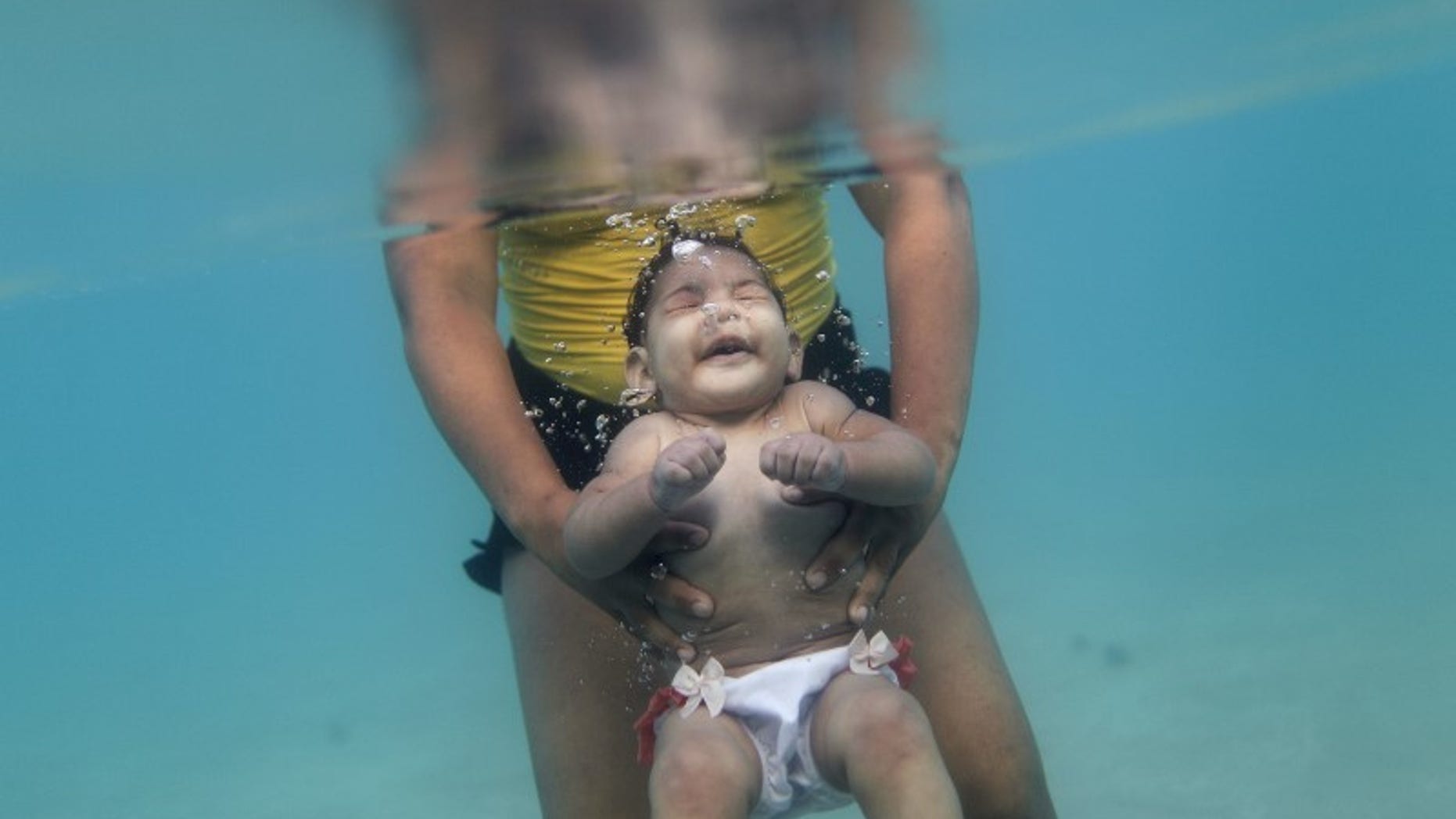 Rosana Vieira Alves and her 5-month-old daughter Luana Vieira, who was born with microcephaly, pose for picture in the sea of Porto de Galinhas, a beach located in Ipojuca