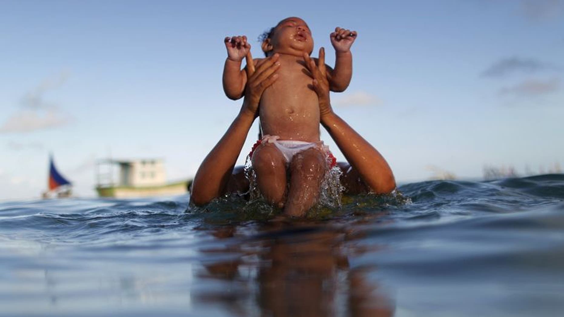 Rosana Vieira Alves and her 5-month-old daughter Luana Vieira, who was born with microcephaly, pose for picture in the sea of Porto de Galinhas, a beach located in Ipojuca