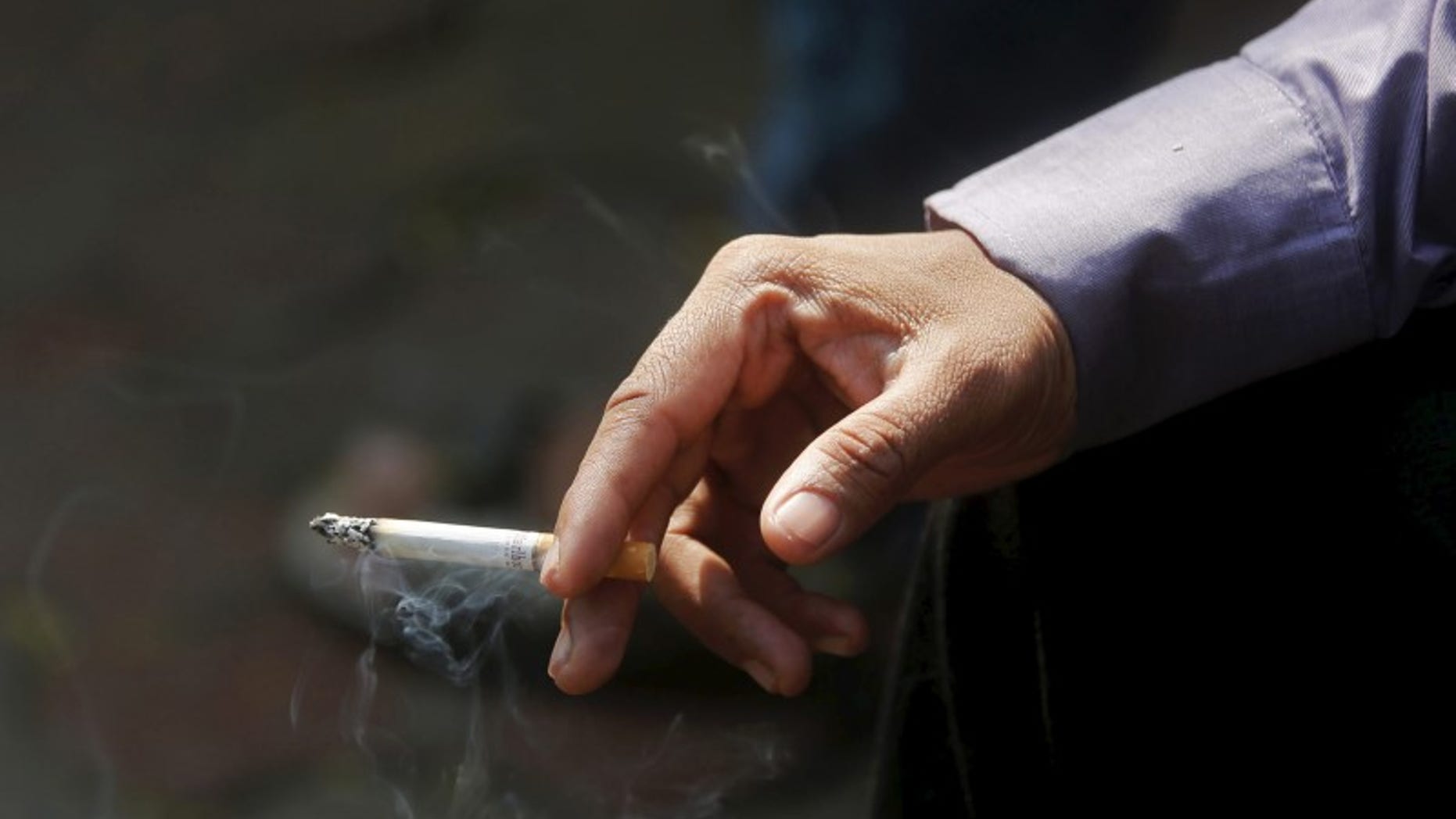 A man smokes a cigarette along a road in Mumbai, India