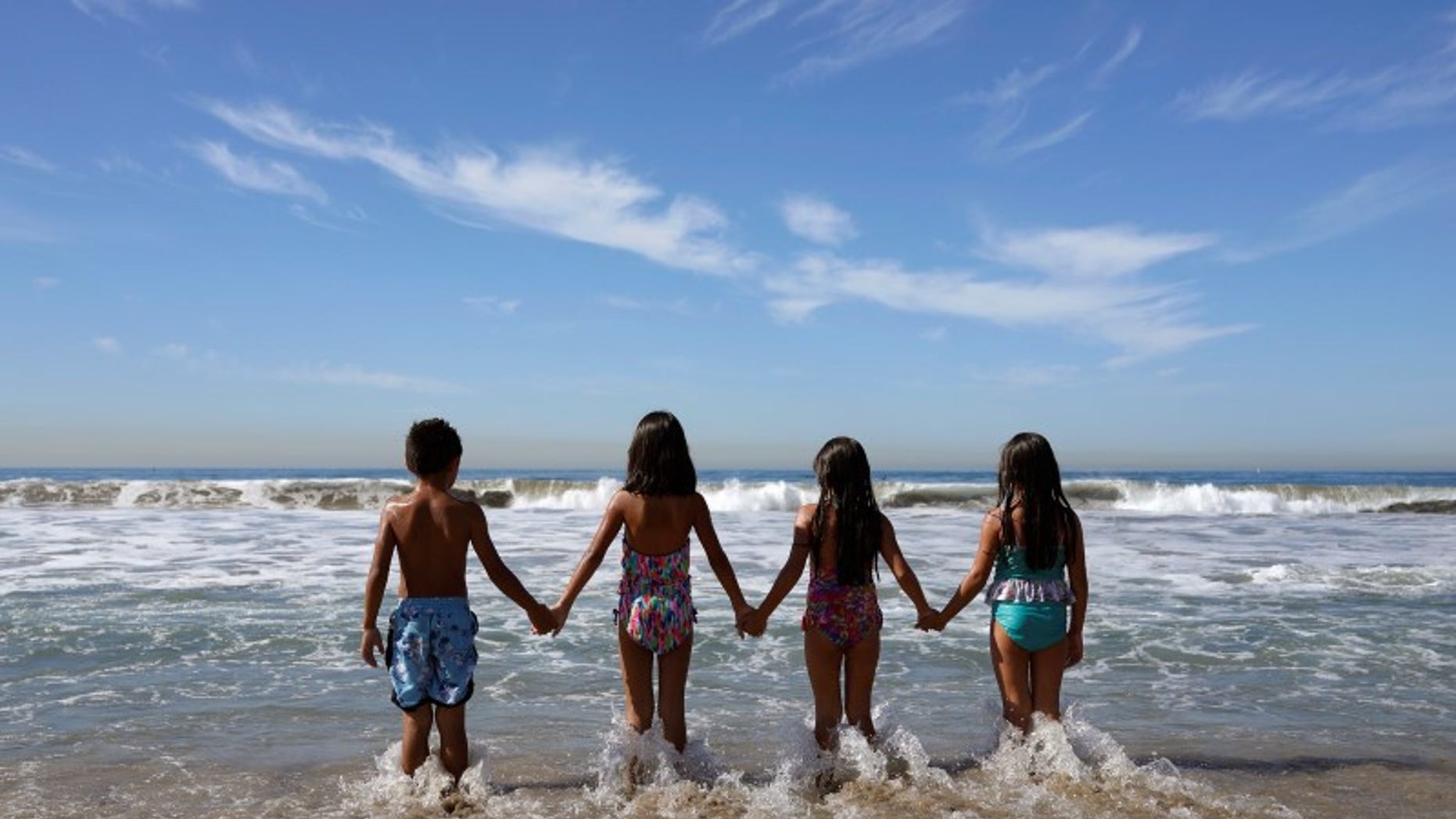 Children walk into the Pacific Ocean in Santa Monica
