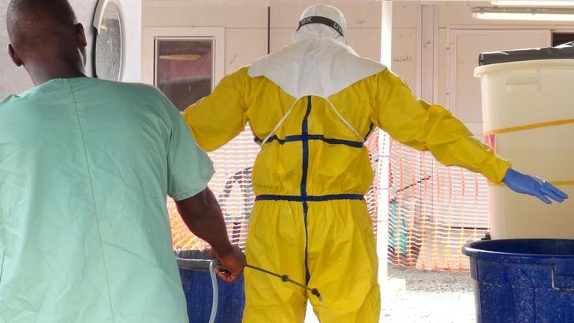A health worker gets sprayed with disinfectant in an Ebola virus treatment center in Conakry