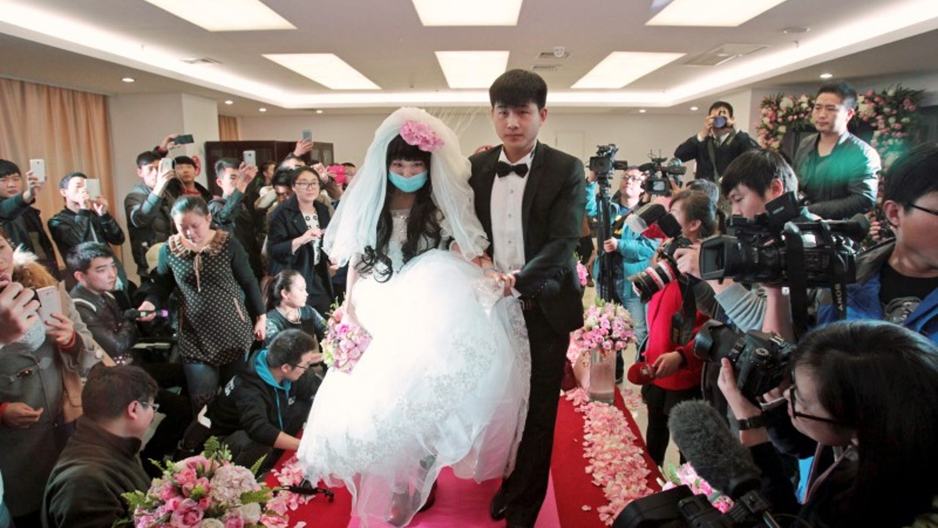 Fan walks on the red carpet with her groom during their wedding at a hospital in Zhengzhou