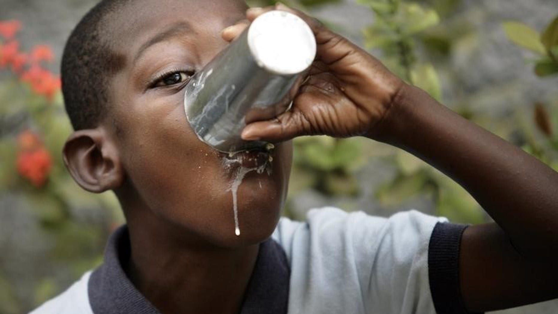 A child drinks milk before the beginning of his class at a make shift school at the slum of Cite-Soleil in Port-au-Prince