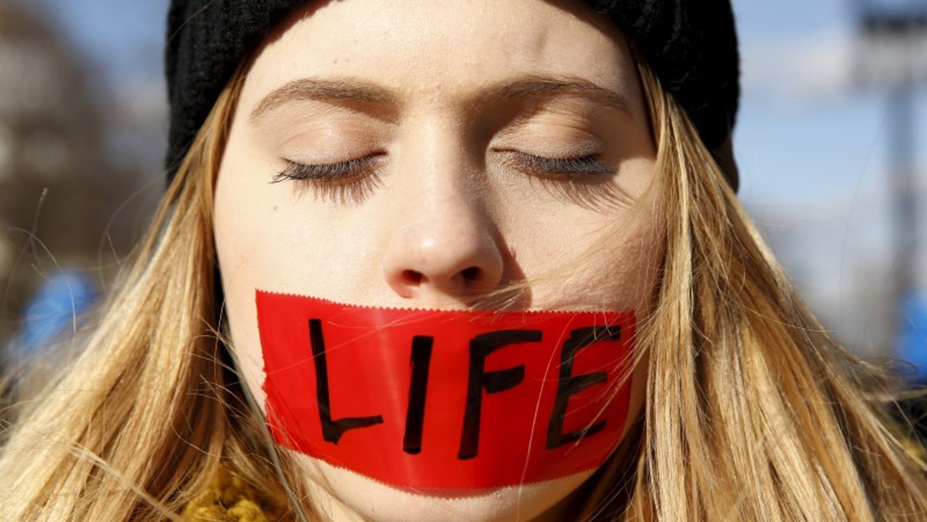 A protester with her mouth taped stands in front of the U.S. Supreme Court in Washington