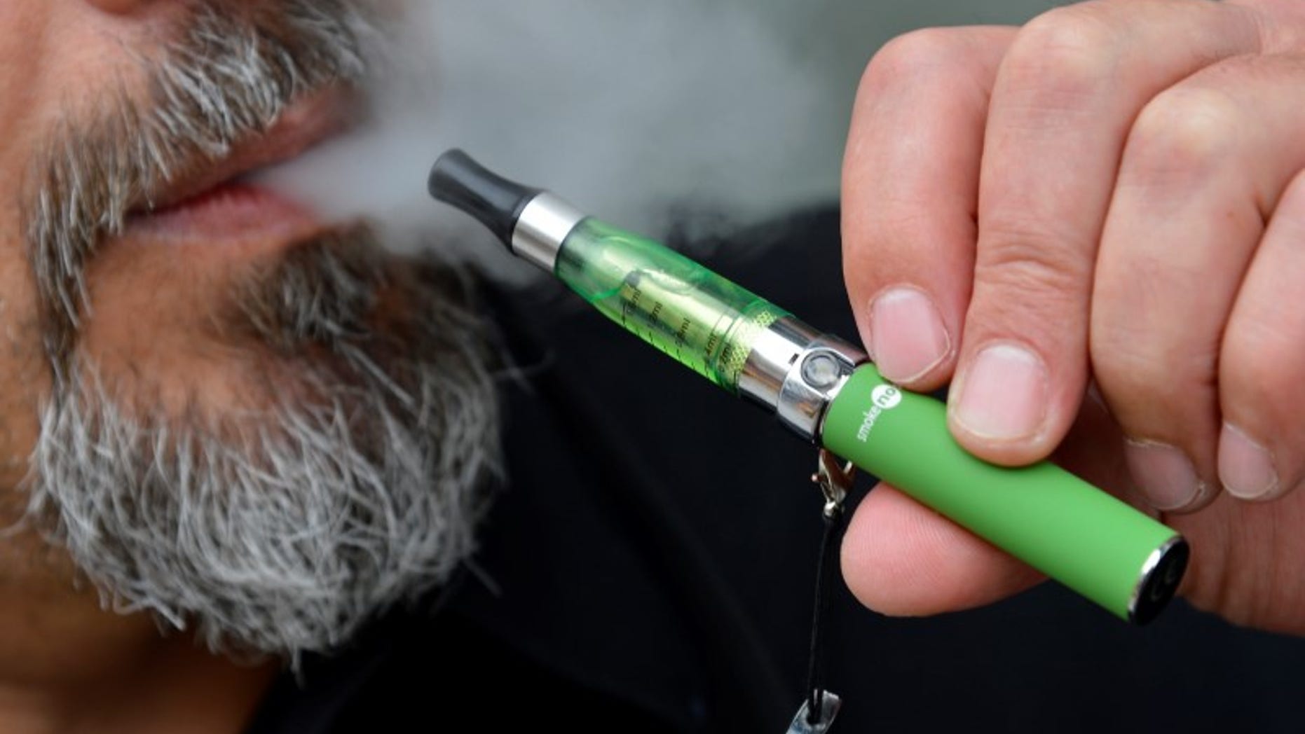 Gabor Kovacs of 'smoke no smoke' puffs on an e-cigarette that his shop sells at Camden in London
