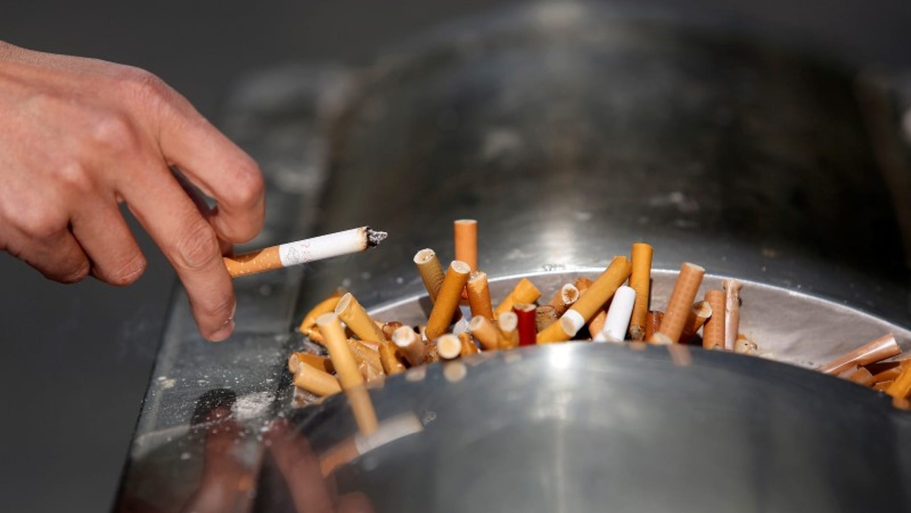 A man flicks ashes from his cigarette over a dustbin in Shanghai