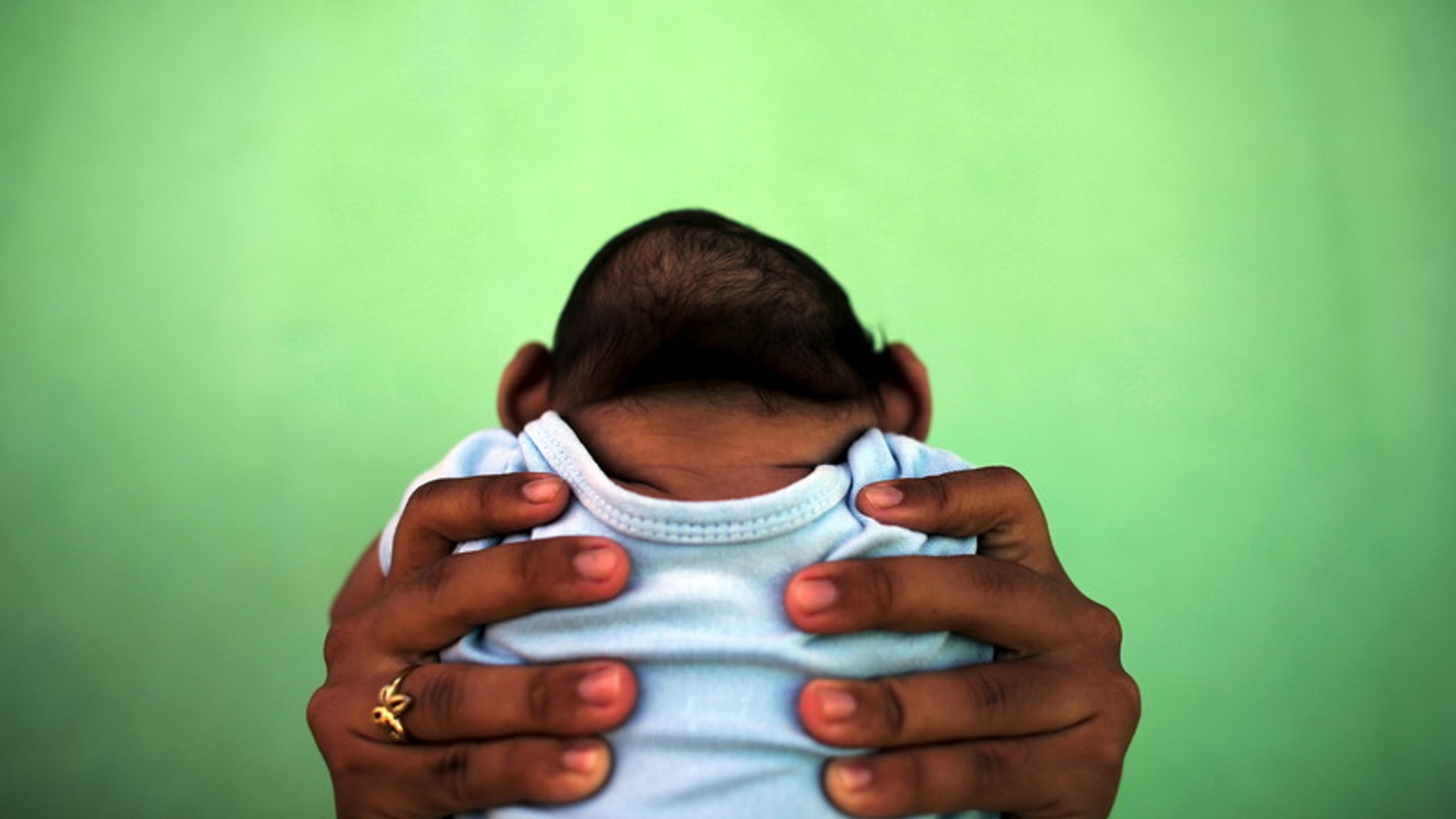 Jackeline, 26, holds her son Daniel who is 4-months old and born with microcephaly, in front of their house in Olinda