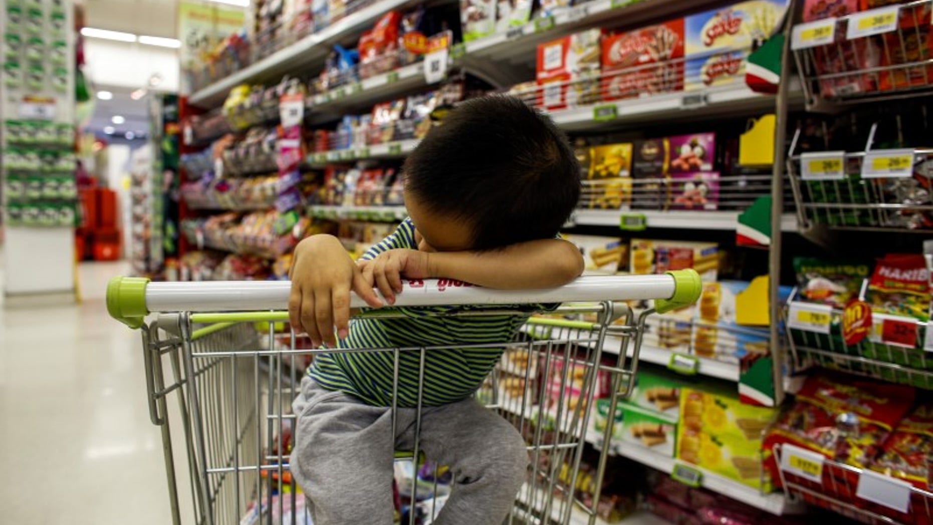 A boy sleeps in a shopping cart at a department store in Bangkok
