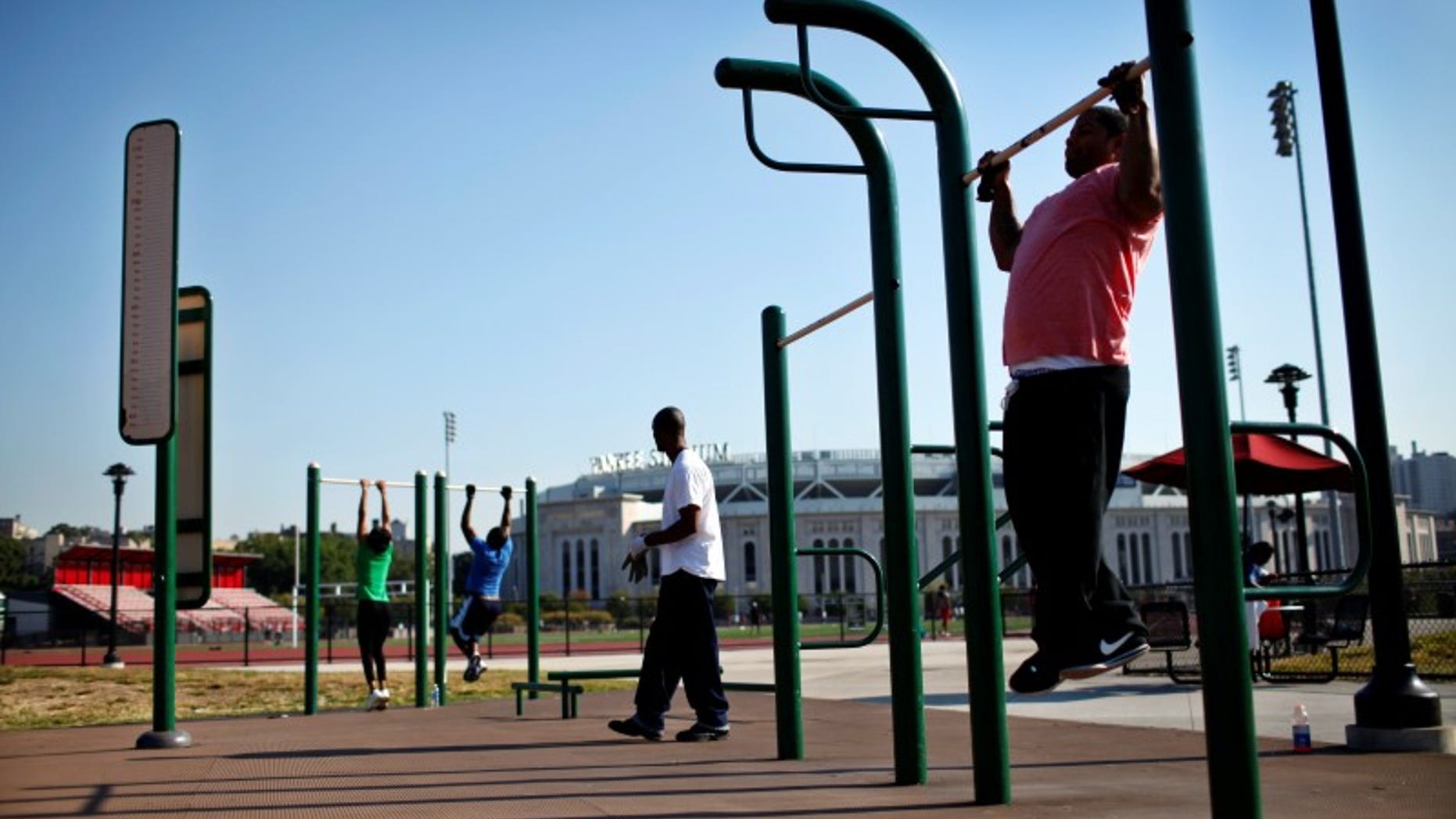 People work out in an outdoor "Adult Playground" exercise area at Macombs Dam Park in the Bronx section of New York City