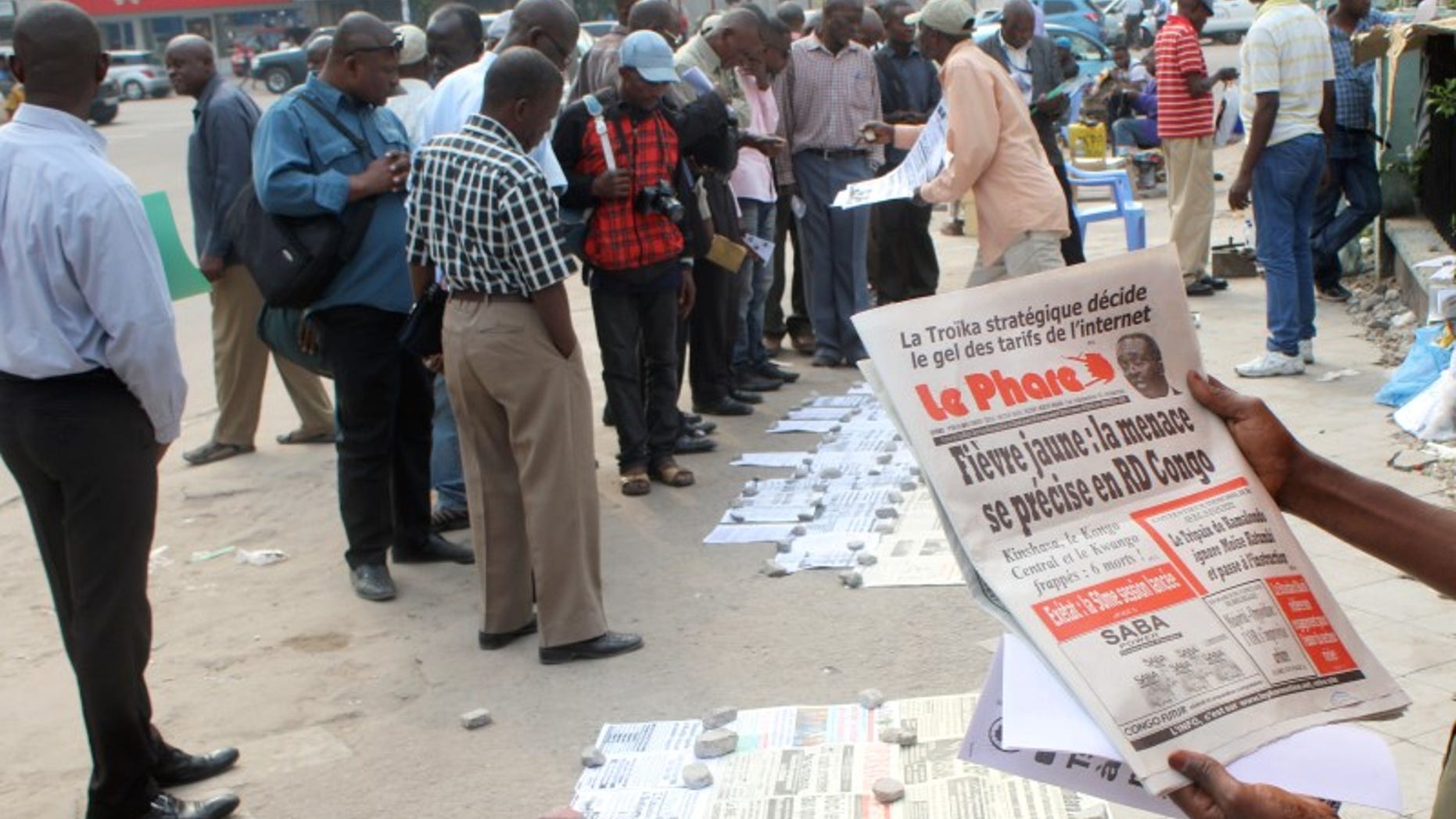 Residents read newspapers with reports of Yellow Fever, in Kinshasa