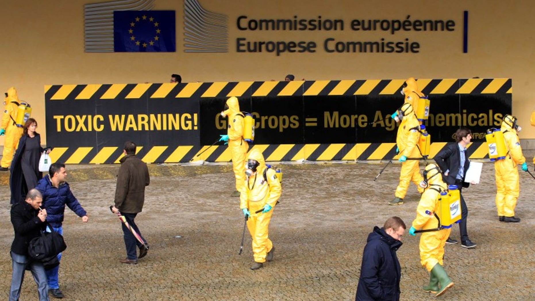 Activists of environmental group Greenpeace wear masks and protective clothing while protesting outside the European Commission headquarters in Brussels