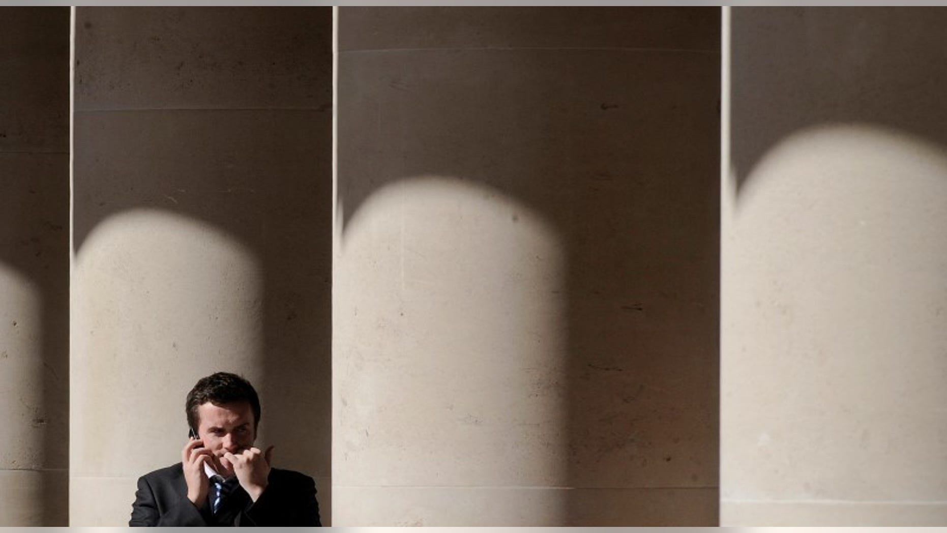 A city worker bites his nails outside the London Stock Exchange in Paternoster Square in the City of London