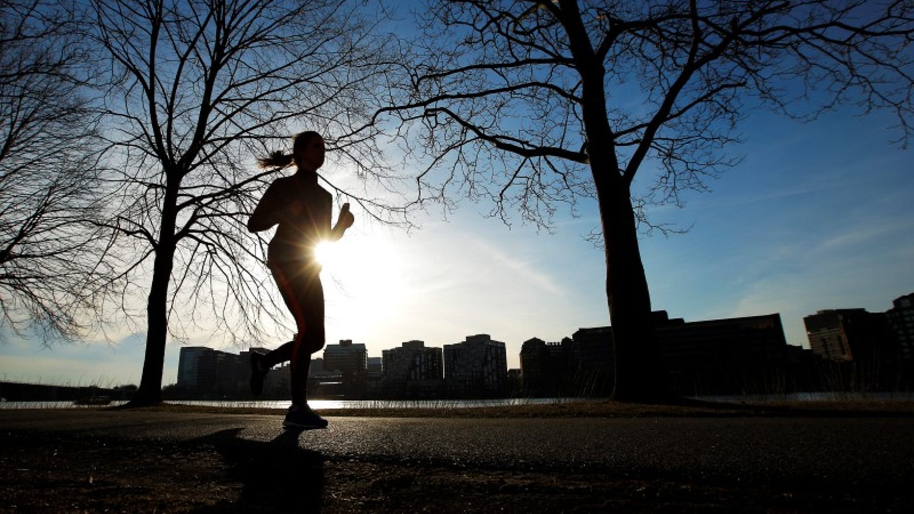 A woman jogs along the Charles River on an early spring evening in Boston.