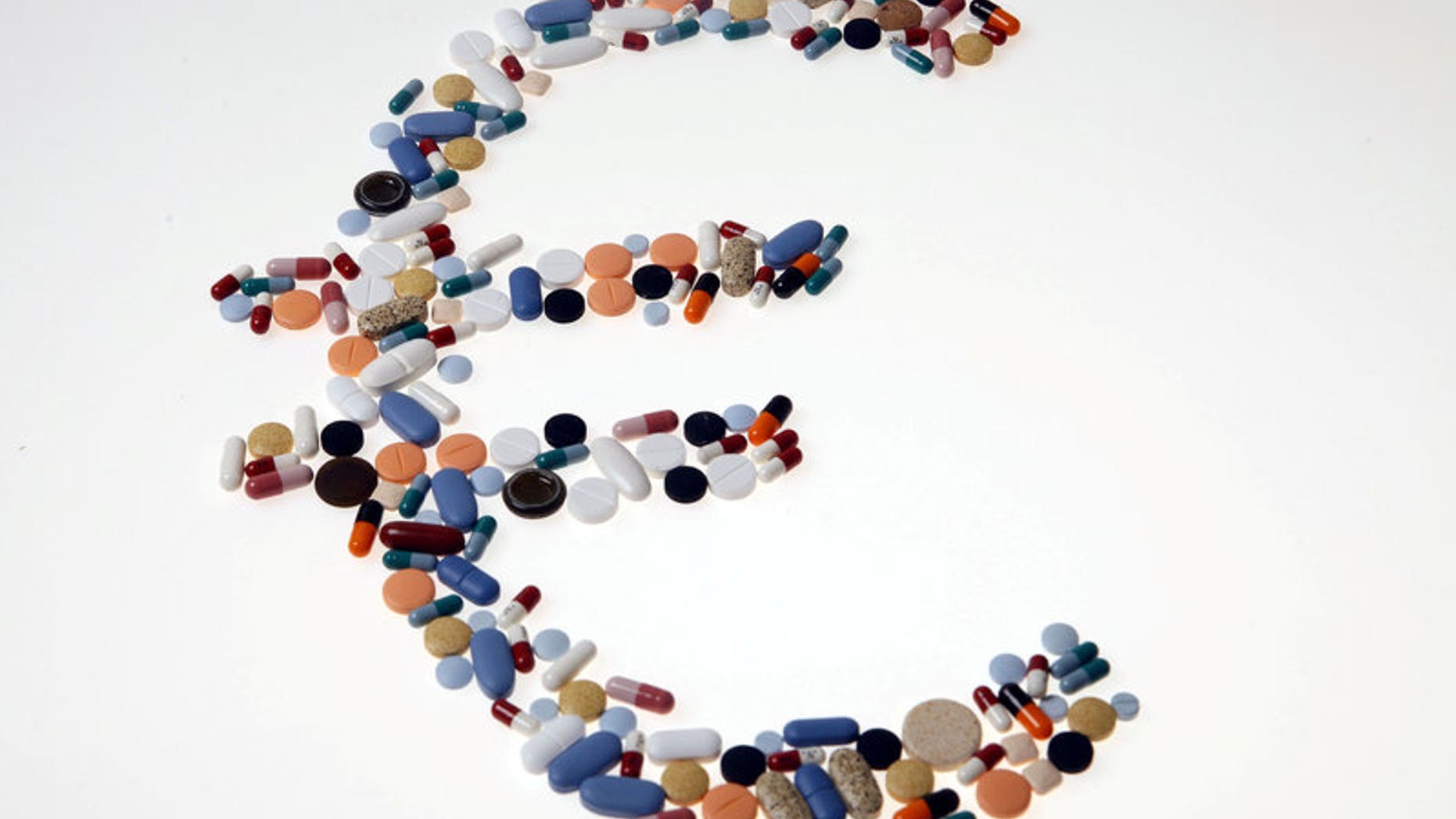Pharmaceutical tablets and capsules are arranged on a table in this picture illustration