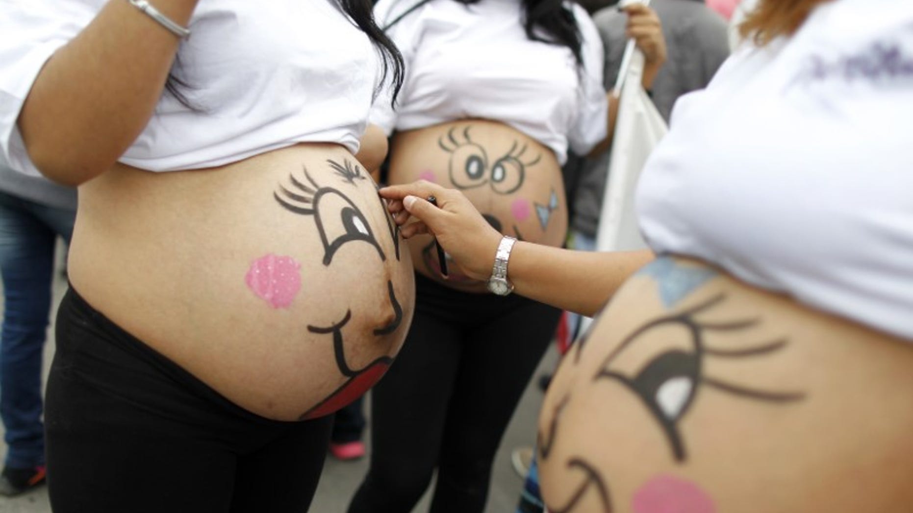 Pregnant women paint their bellies before an event to celebrate "Healthy Maternity Week" in Lima
