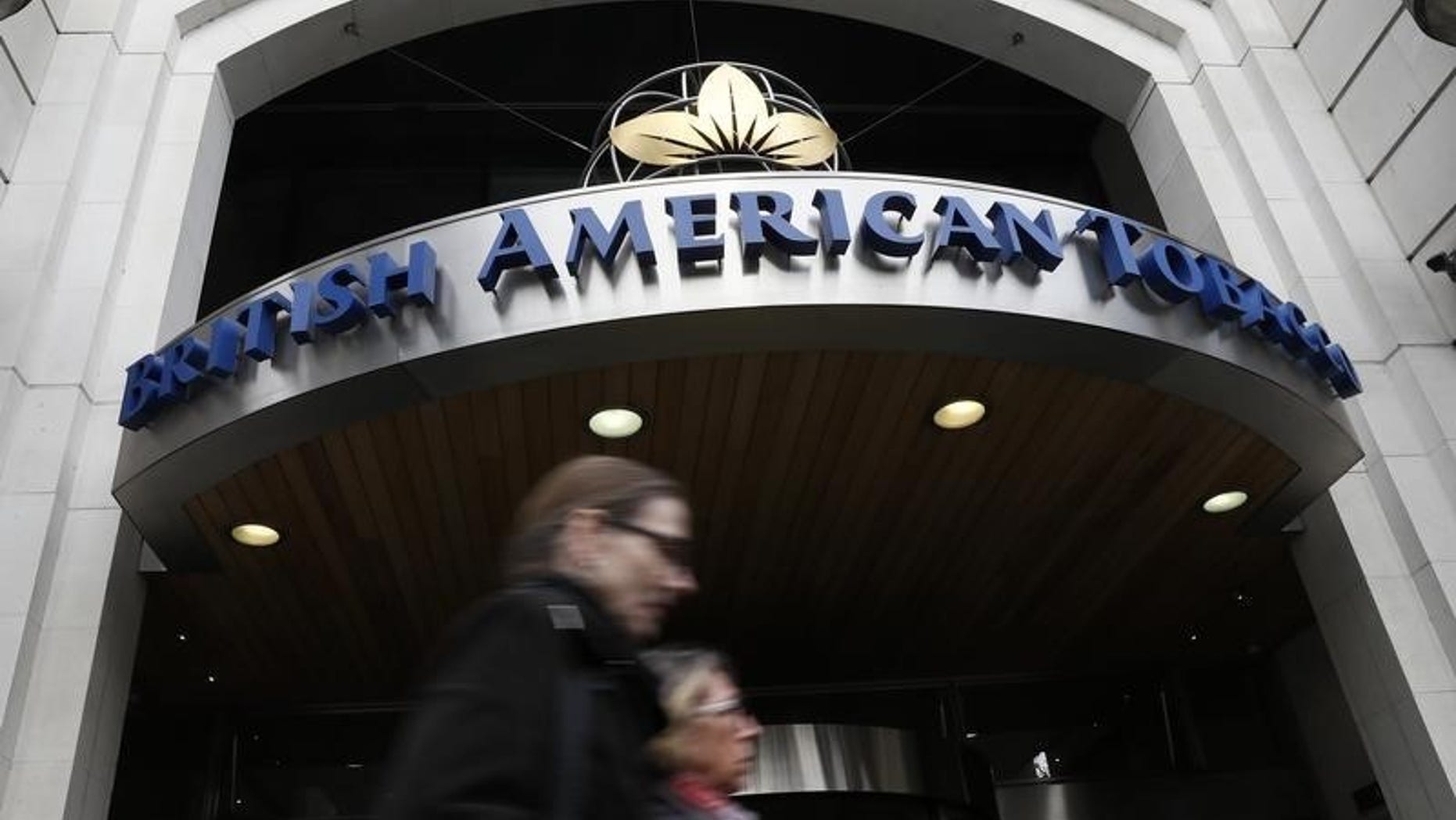 People walk past the British American Tobacco offices in London