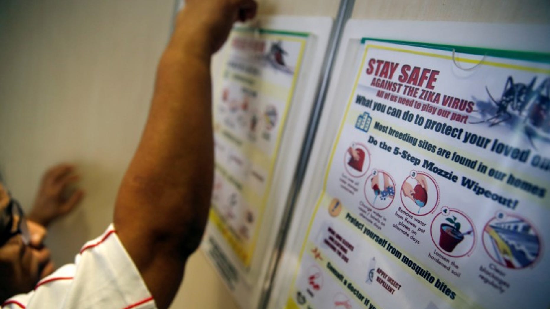 A resident volunteer puts up posters in a lift of a public housing estate in a Zika cluster in Singapore