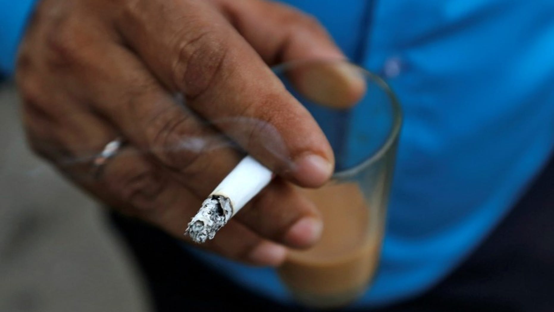 A man smokes a cigarette along a road in Mumbai