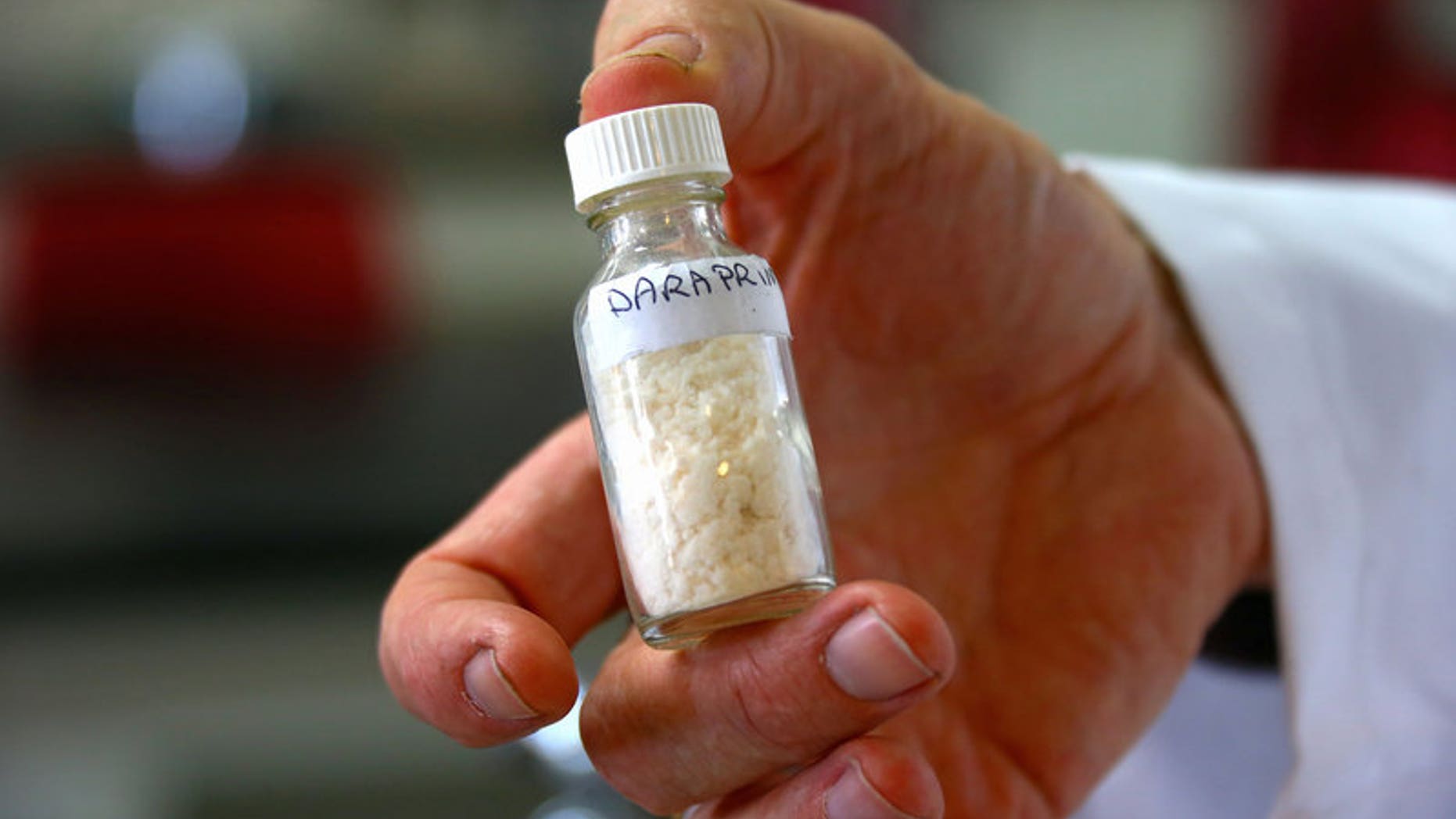 School teacher Dr Malcolm Binns holds a small jar of the compound of an anti-parasitic medicine used to treat malaria, called Daraprim, which was partly made by his students in a lab at Sydney Grammar School in Sydney