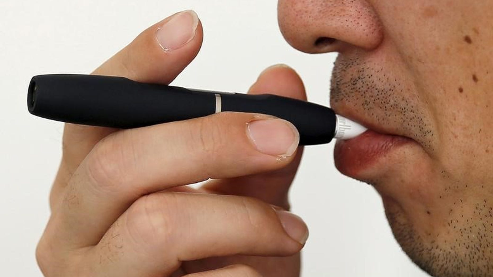 A customer tries a Philip Morris' "iQOS" smokeless tobacco at an iQOS store in Tokyo
