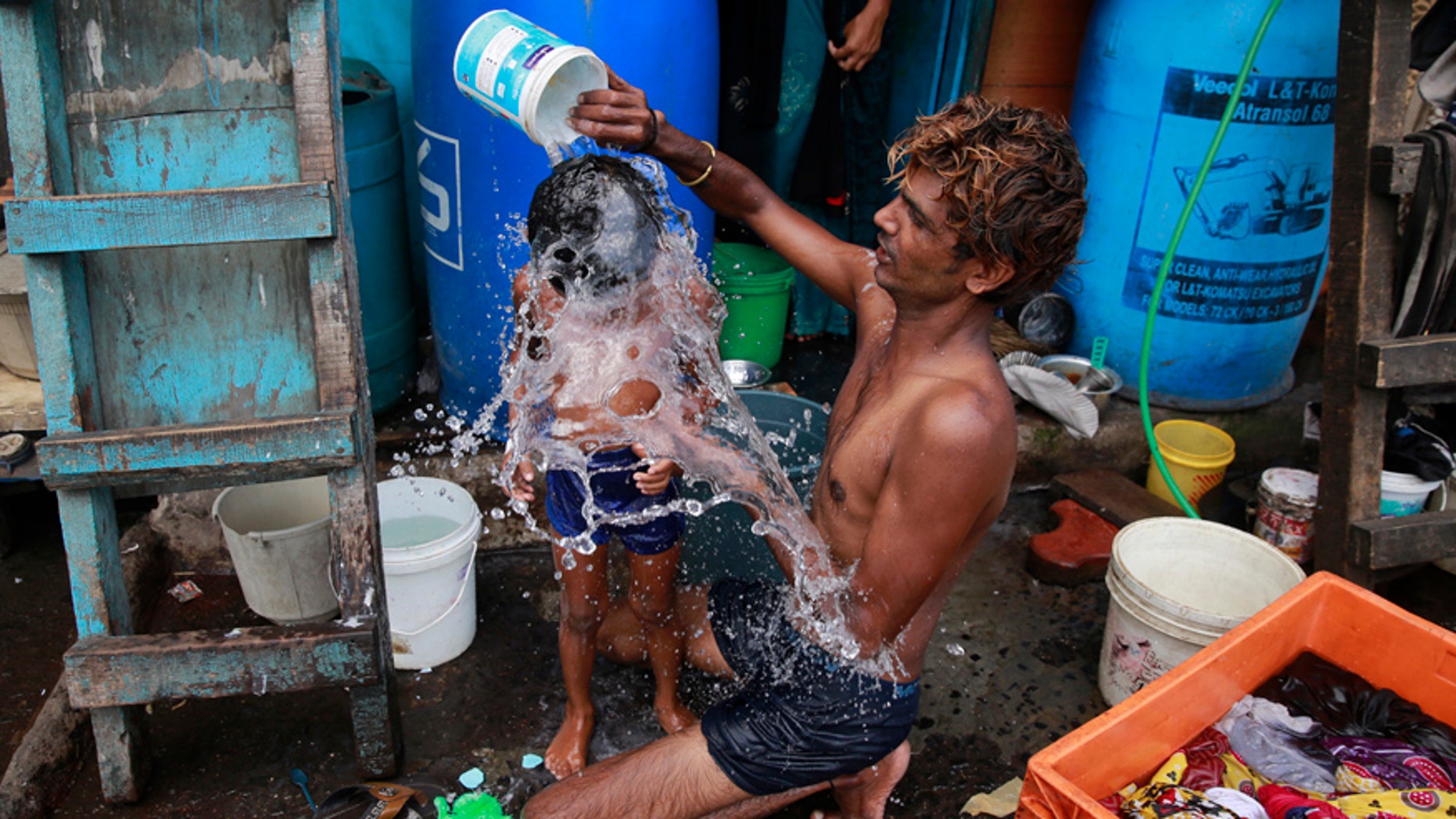 In this May 23, 2016, file photo, a man bath his son on a hot afternoon in a slum in Mumbai, India. For the third straight year, Earth set a record for the hottest year, NOAA and NASA announced.