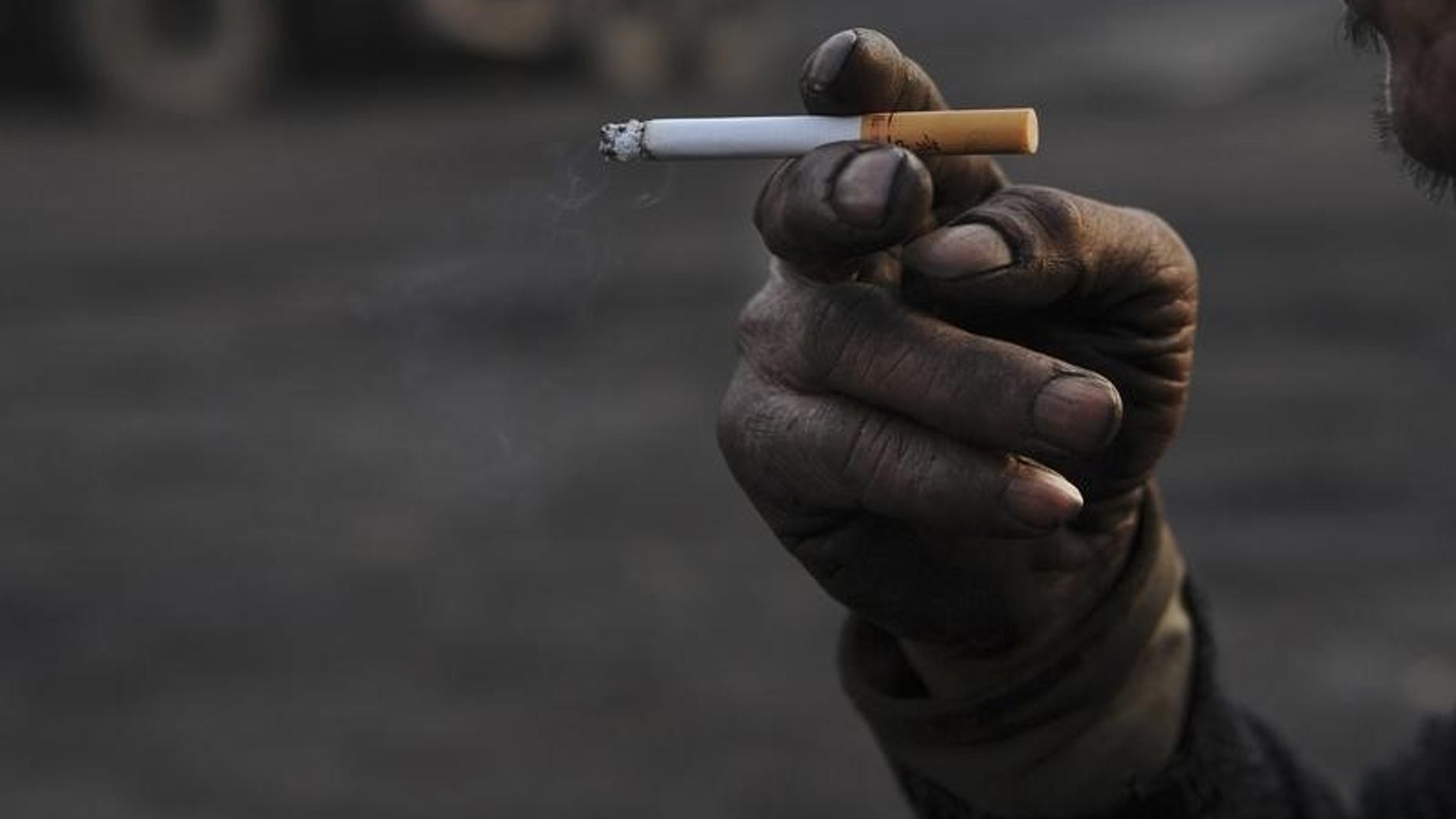 Worker smokes cigarette during a break at a coal freight yard in Hefei