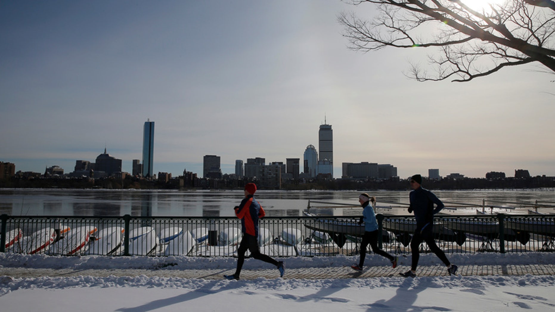 Joggers run along the Charles River past the Boston skyline on a sunny winter's day in Cambridge.
