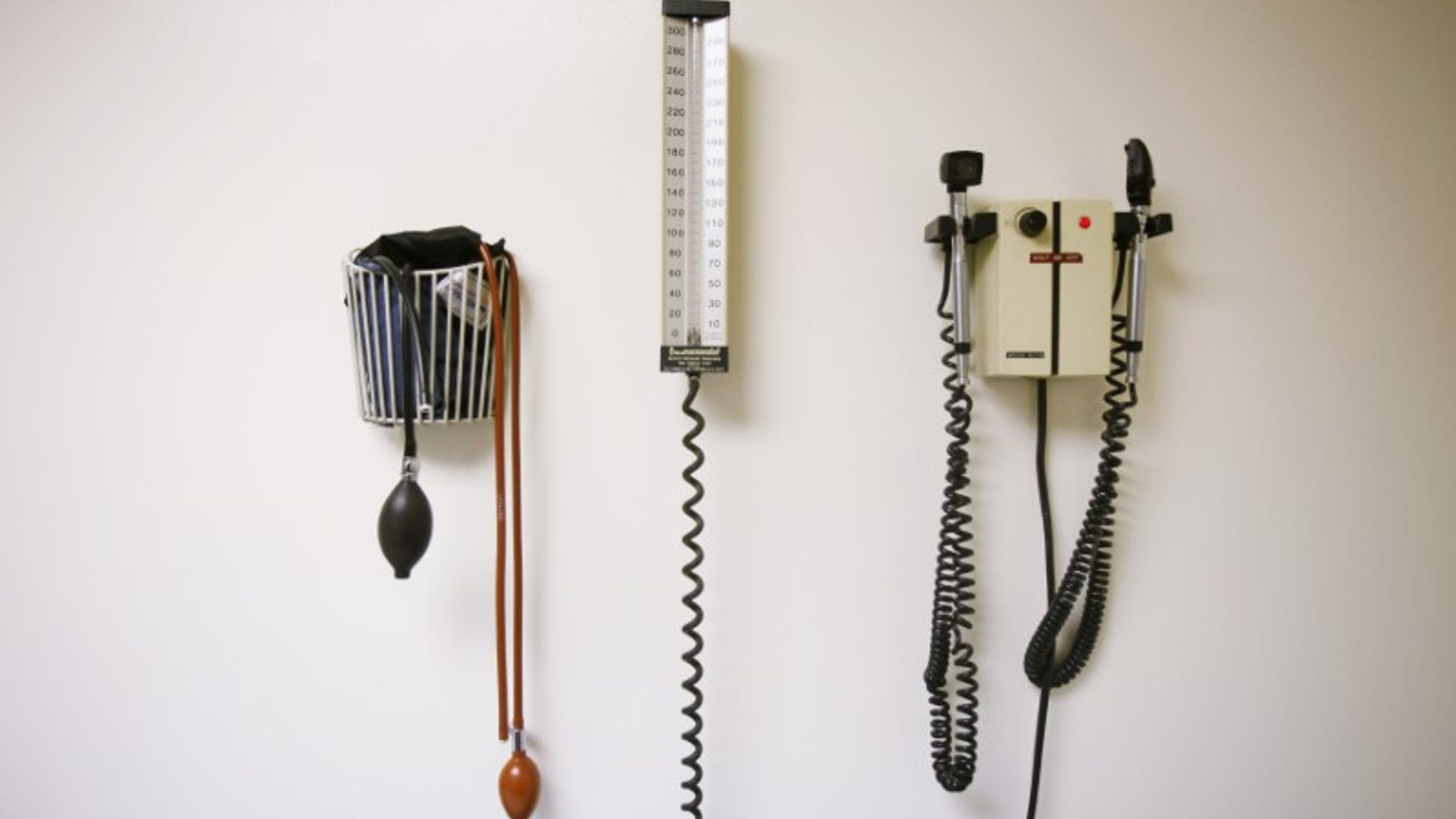Devices used to take blood pressure, temperature, and examine eyes and ears rest on a wall inside of a doctor's office in New York