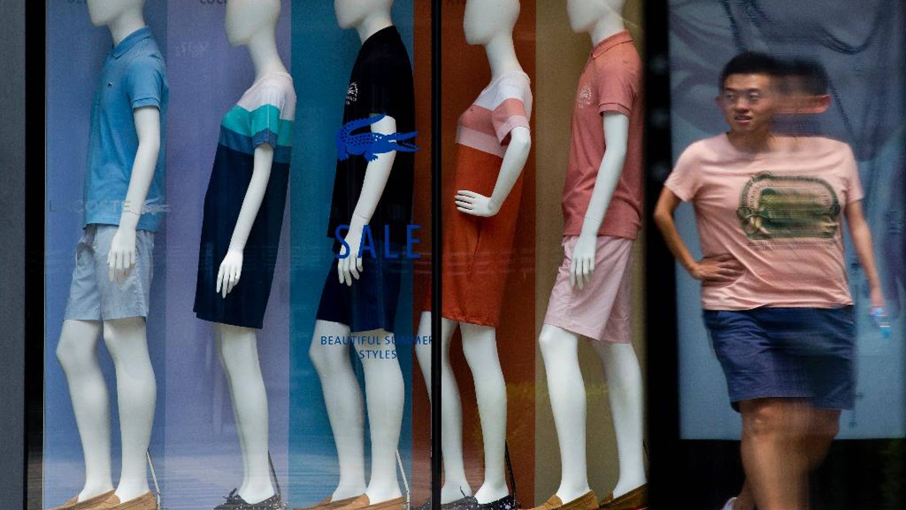 A man walks past mannequins with various fashion design clothes on display at a boutique in Beijing Tuesday, July 14, 2015. China's June export growth rebounded to 2.8 percent in a modest improvement amid slowing economic growth while imports fell 6.1 percent. (AP Photo/Andy Wong)