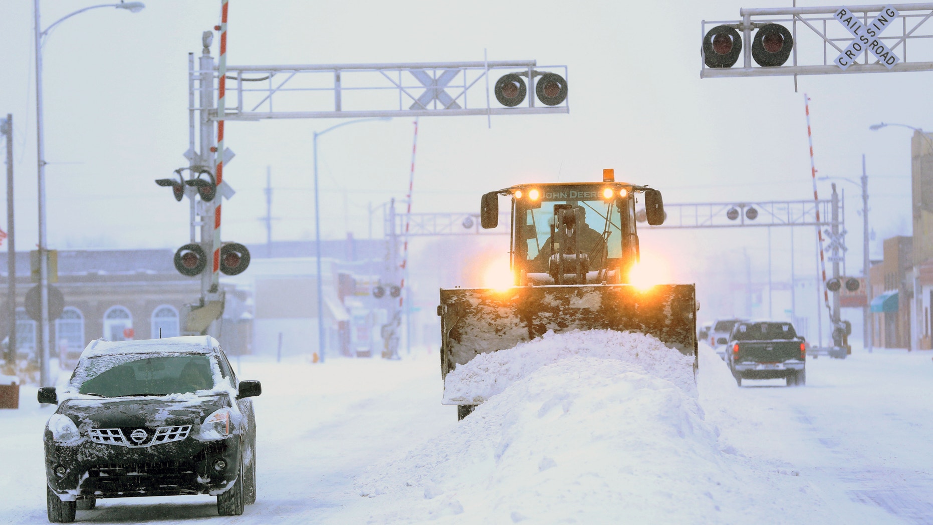 A City of Hutchison, Kan., front end loader clears snow from intersections on S. Main St. Tuesday, Feb. 4, 2014. The winter storm dumped more than 10 inches of snow on the city from late Monday to late Tuesday. (AP Photo/The Hutchinson News, Travis Morisse)