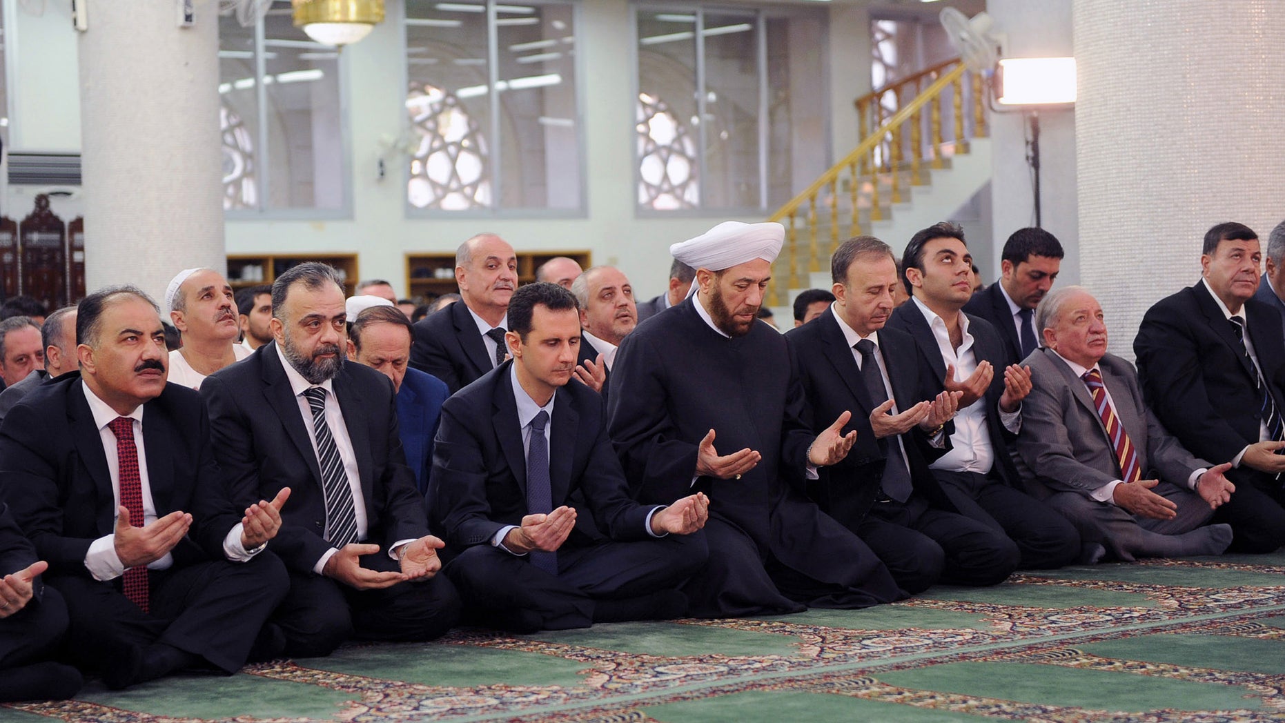 In this photo released by the Syrian official news agency SANA, Syrian President Bashar Assad, third left, prays on the first day of Eid al-Adha at the Sayeda Hassiba mosque, in Damascus, Syria, Tuesday, Oct. 15, 2013. (AP Photo/SANA)