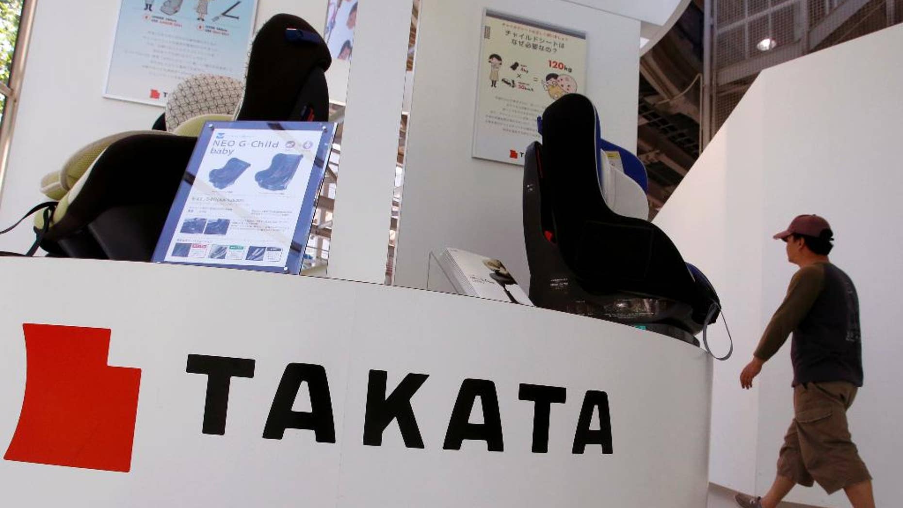 FILE - In this Wednesday, May 4, 2016 file photo, a visitor walks past child seats, manufactured by Takata Corp., displayed at an automaker's showroom in Tokyo. A criminal complaint has been filed in Japan about a Takata air bag causing injuries during a crash, the first such case in this nation related to an unfolding massive recall. Takata Corp. said Wednesday, June 8, 2016, it was fully cooperating with the investigation of the accident, in which a woman in the front passenger seat of a Nissan X-Trail sport-utility vehicle was injured.(AP Photo/Shizuo Kambayashi, File)