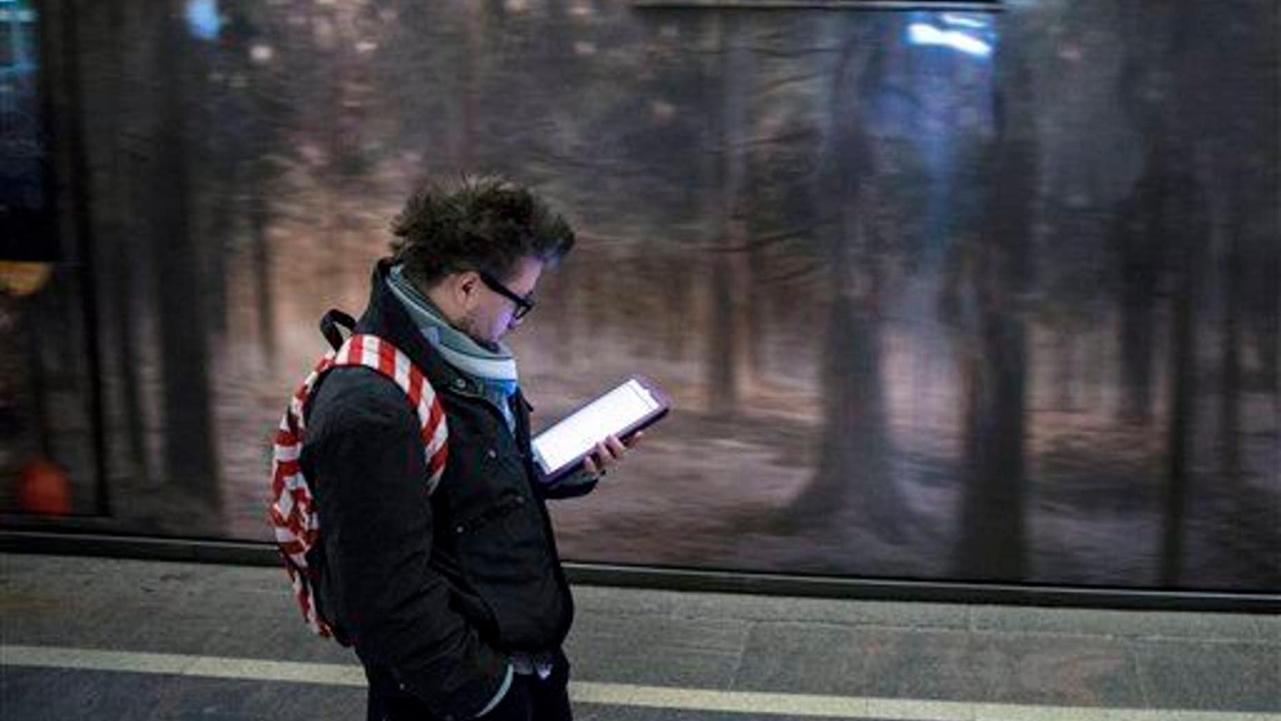 A man surfs the Internet on his tablet in a Moscow subway, Russia, Wednesday, April 8, 2015.